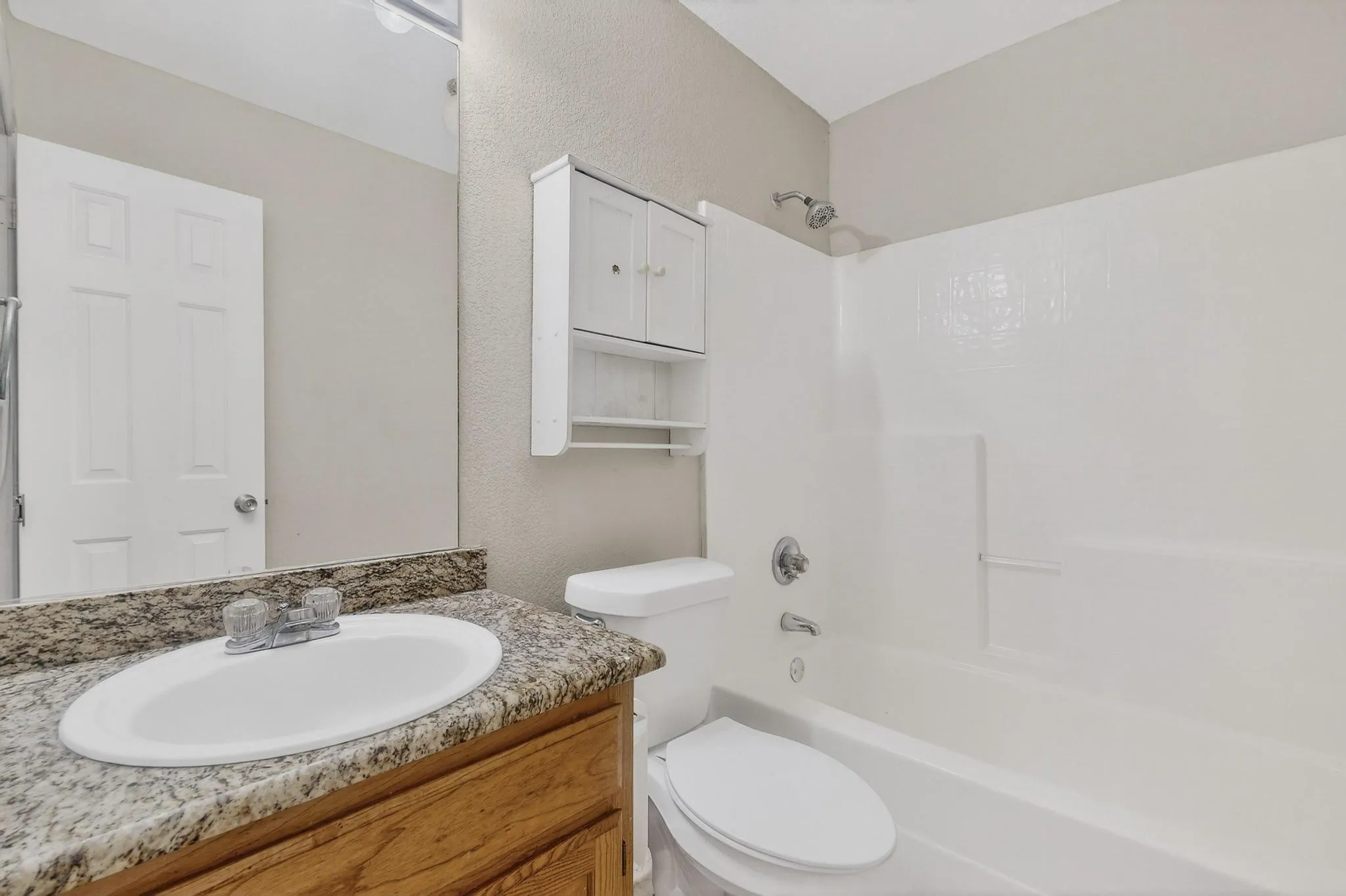 Vanity with a granite-style countertop, undermount sink, and wood-finish cabinetry