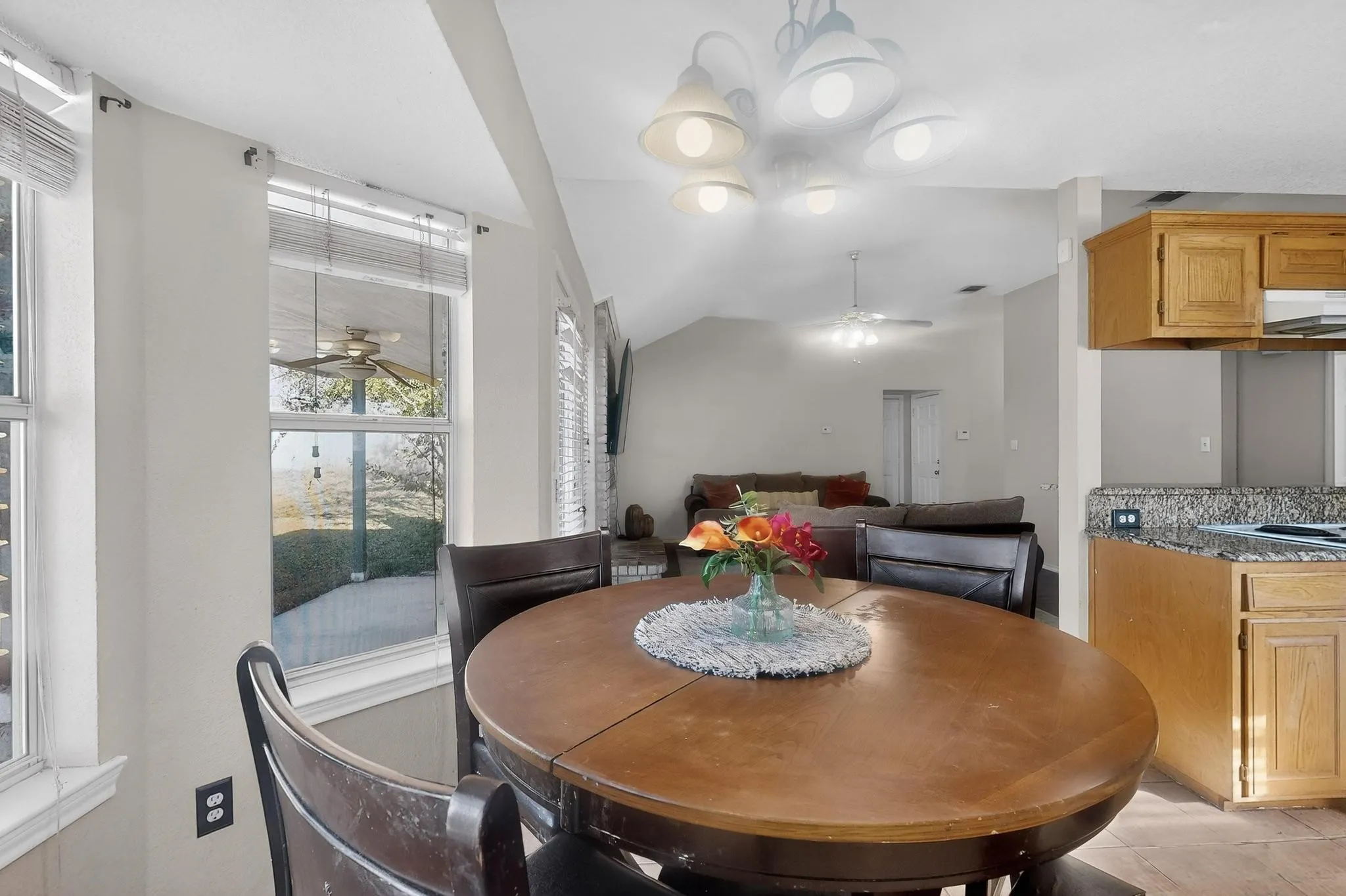 Open concept living area with vaulted ceilings, featuring a dining area, kitchen with wood cabinetry, and a living room