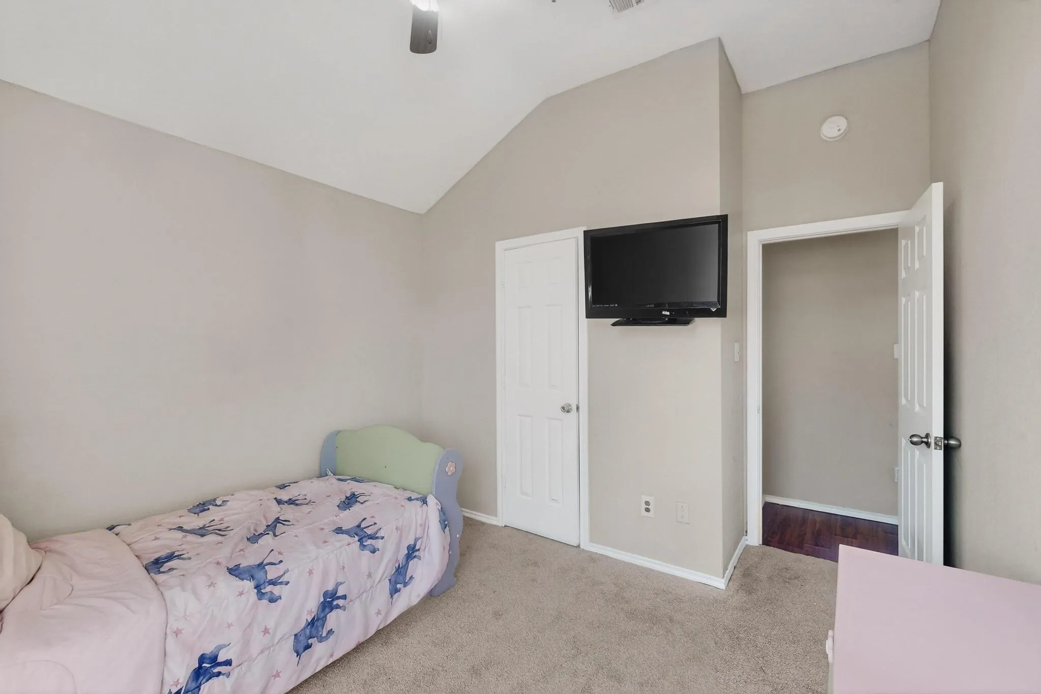 Vaulted ceiling, ceiling fan, neutral wall tones, carpet flooring, interior door