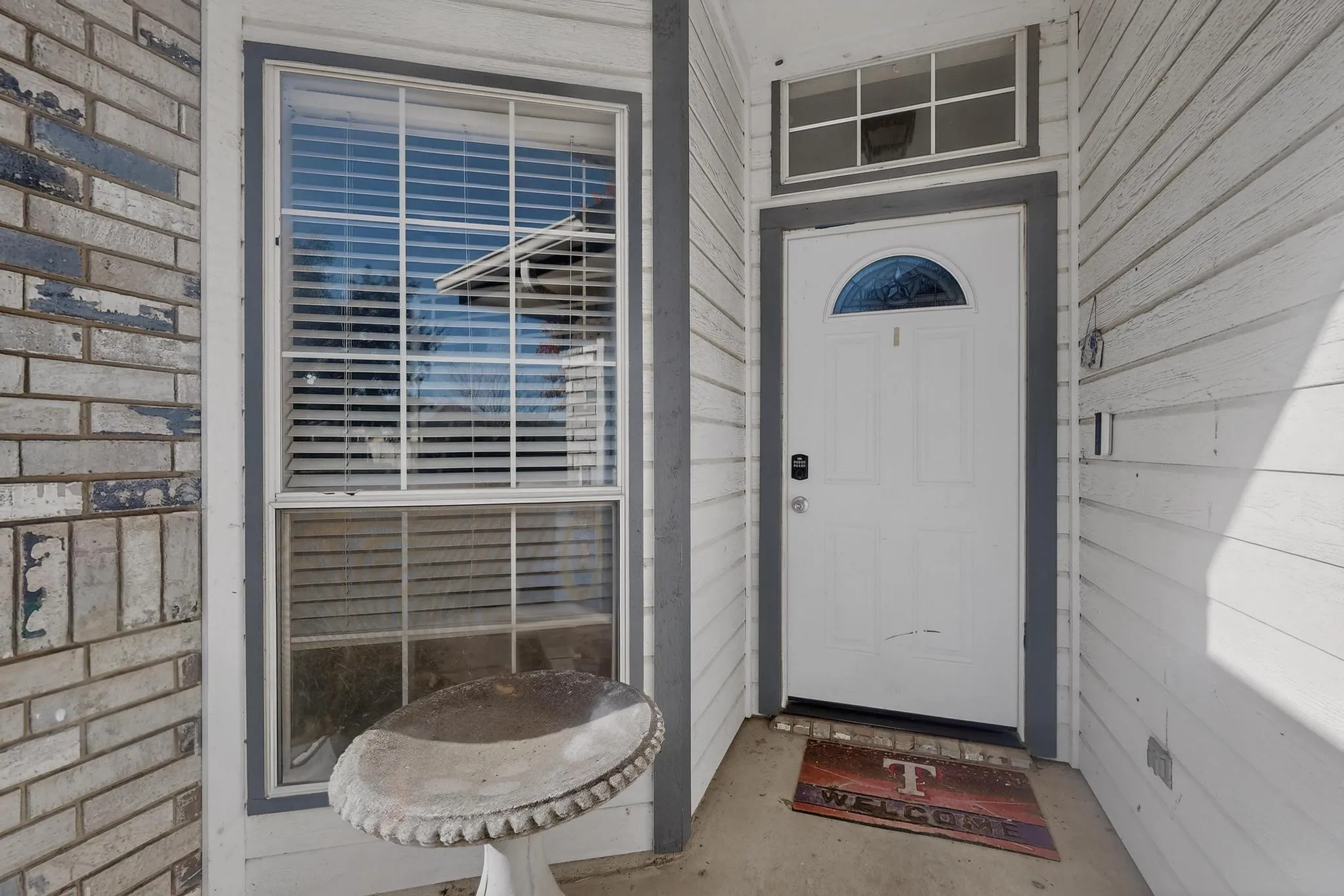 White paneled door with an arched glass insert, transom window, and digital keypad entry