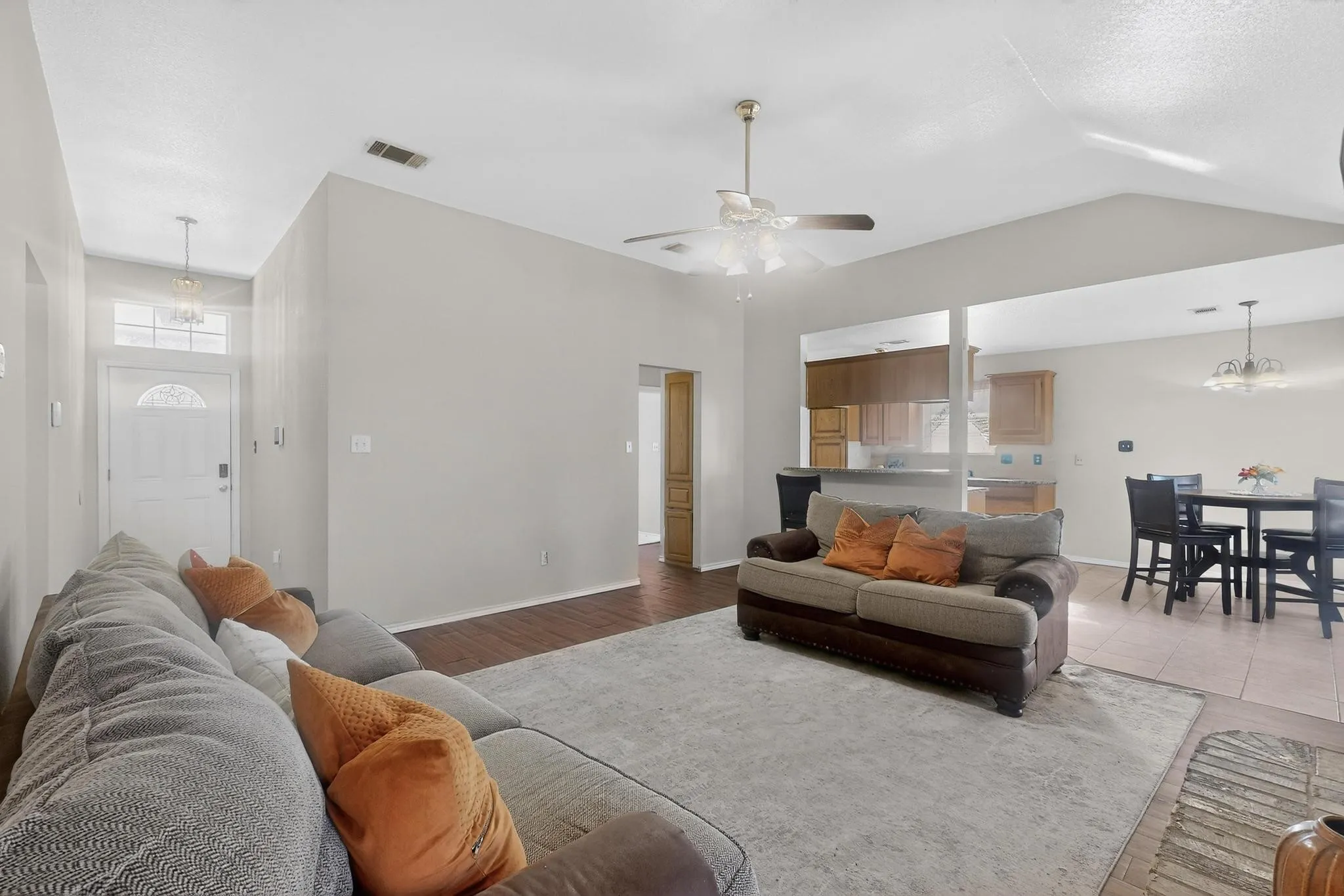 Vaulted ceiling, wood-finish flooring, ceiling fan, and tile flooring