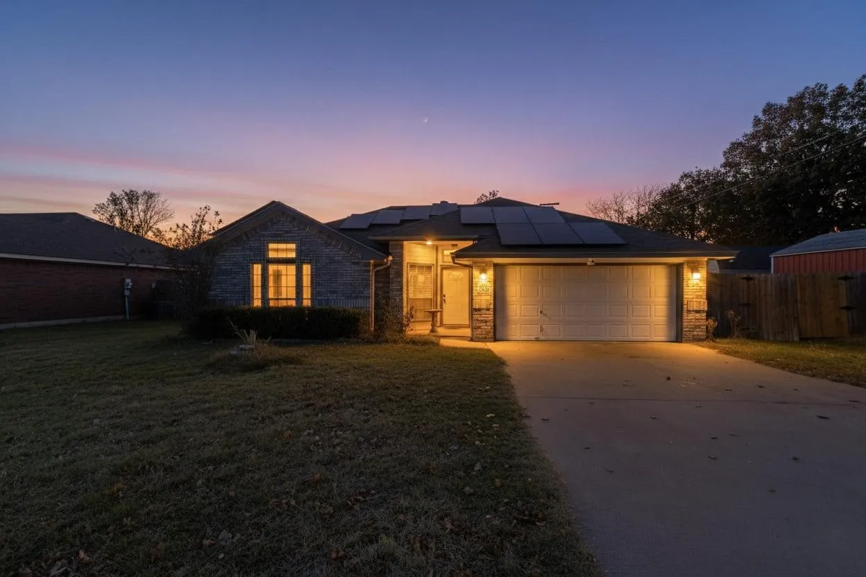 Brick and stone exterior with a two-car garage, solar panels, and a concrete driveway
