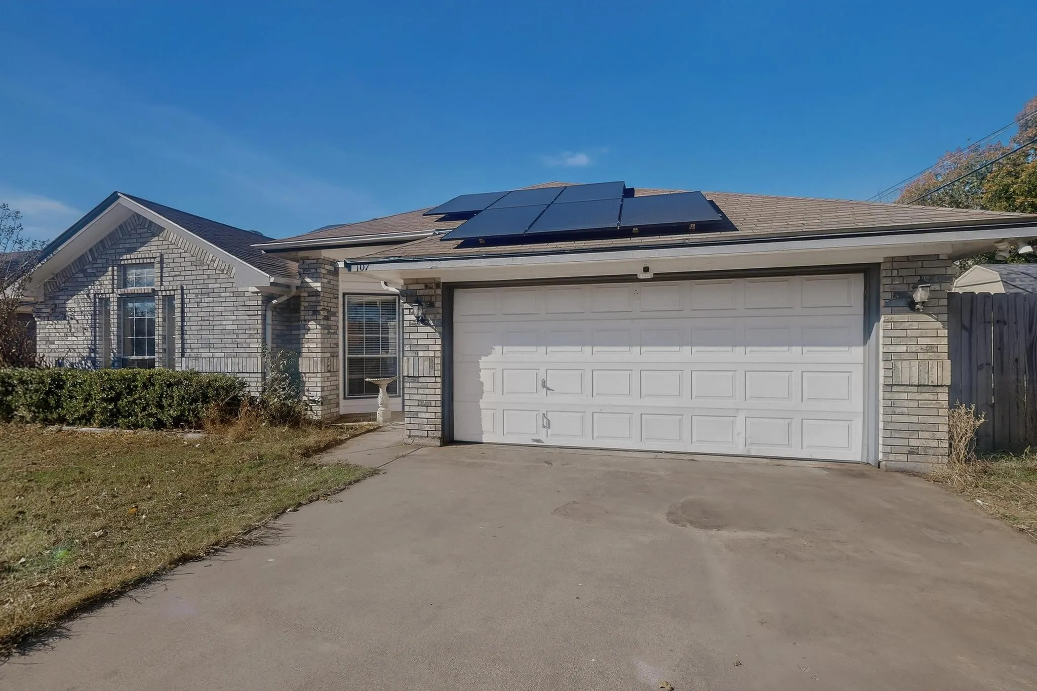 Brick exterior with solar panels, an attached two-car garage, and a concrete driveway