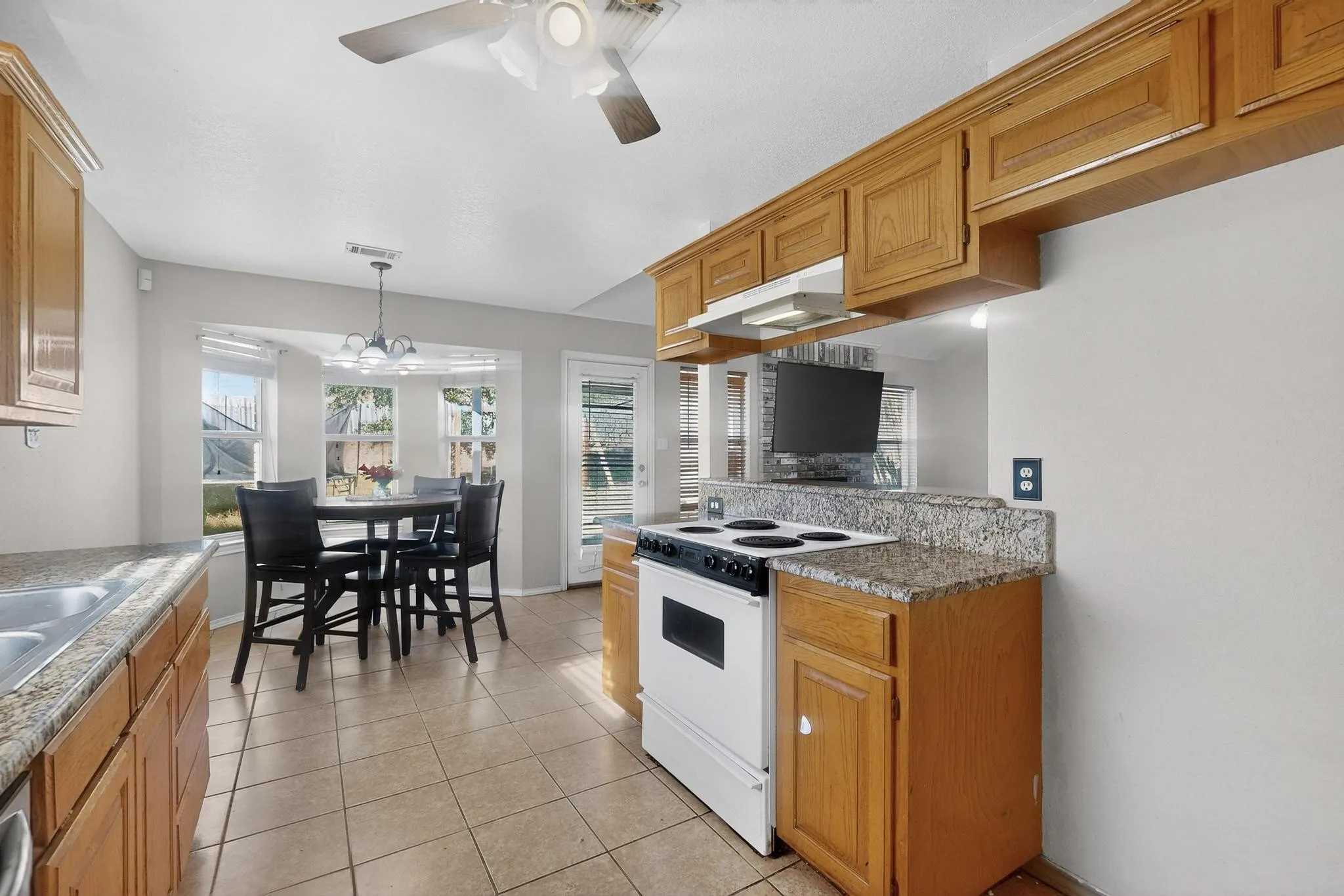 Wood-finish cabinetry, tile flooring, and granite-style countertops
