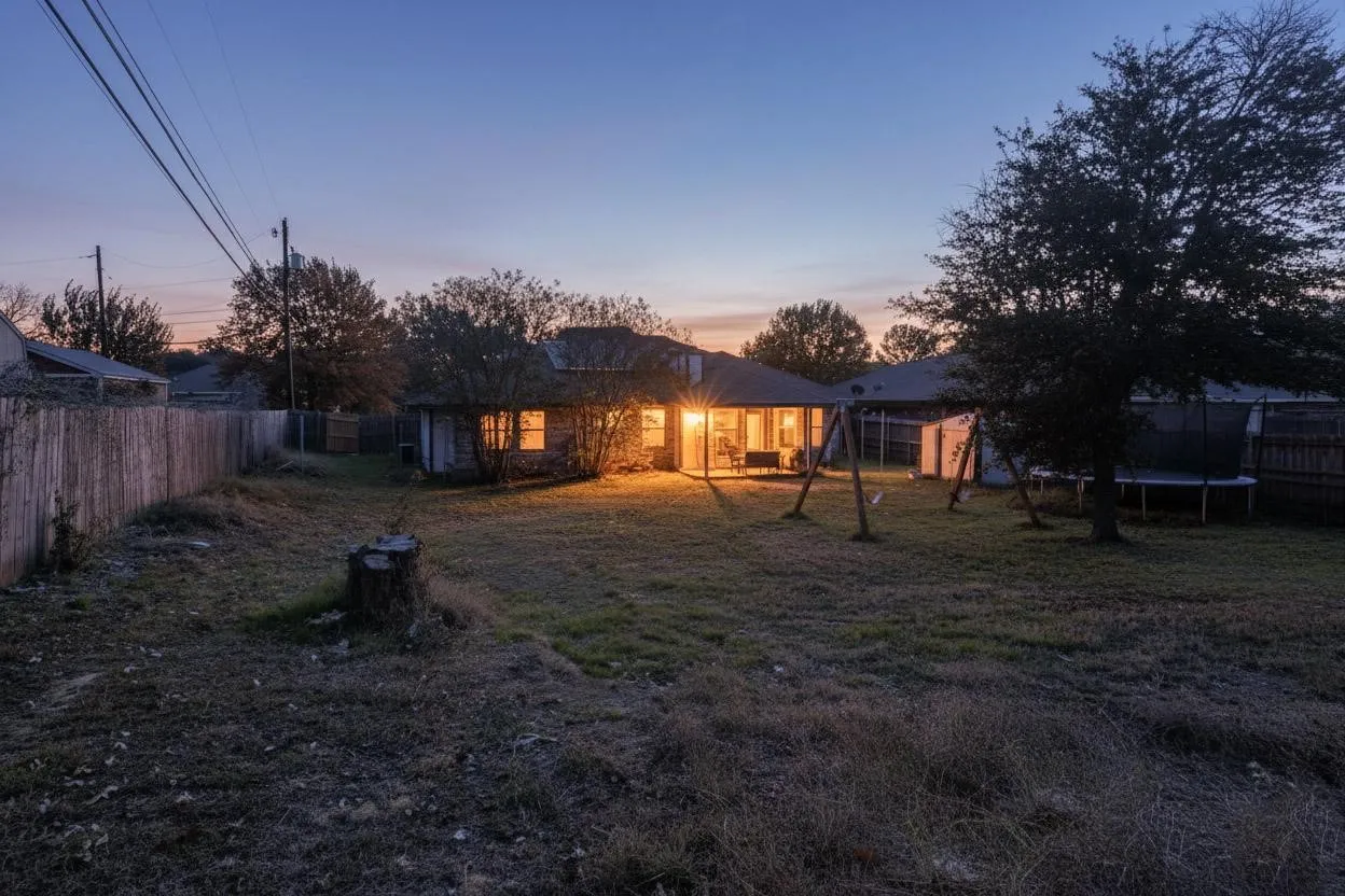 Expansive backyard featuring a wood fence, mature trees, and a covered patio with recessed lighting