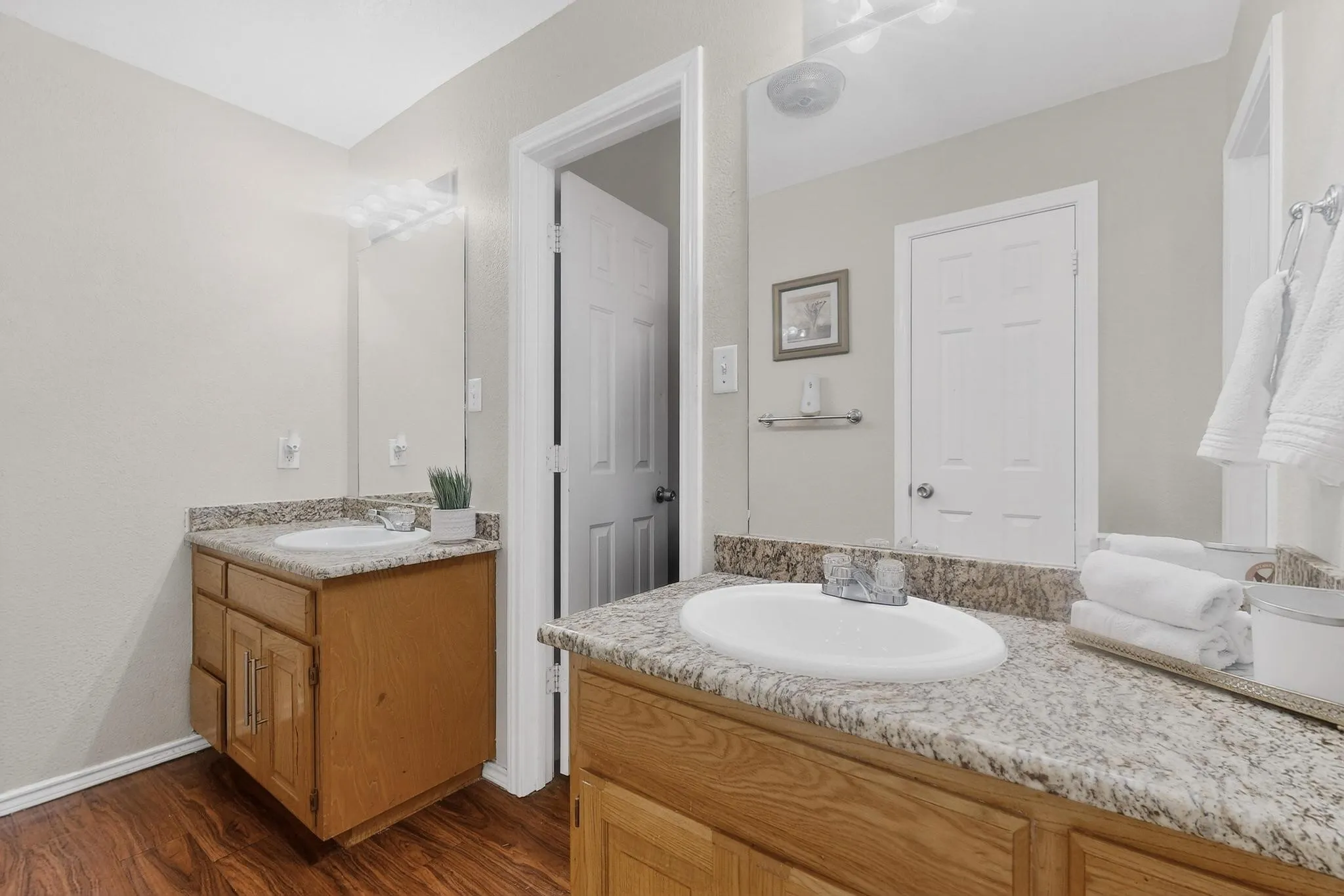 Dual vanity with wood-finish cabinetry, speckled countertops, and under-mount sinks