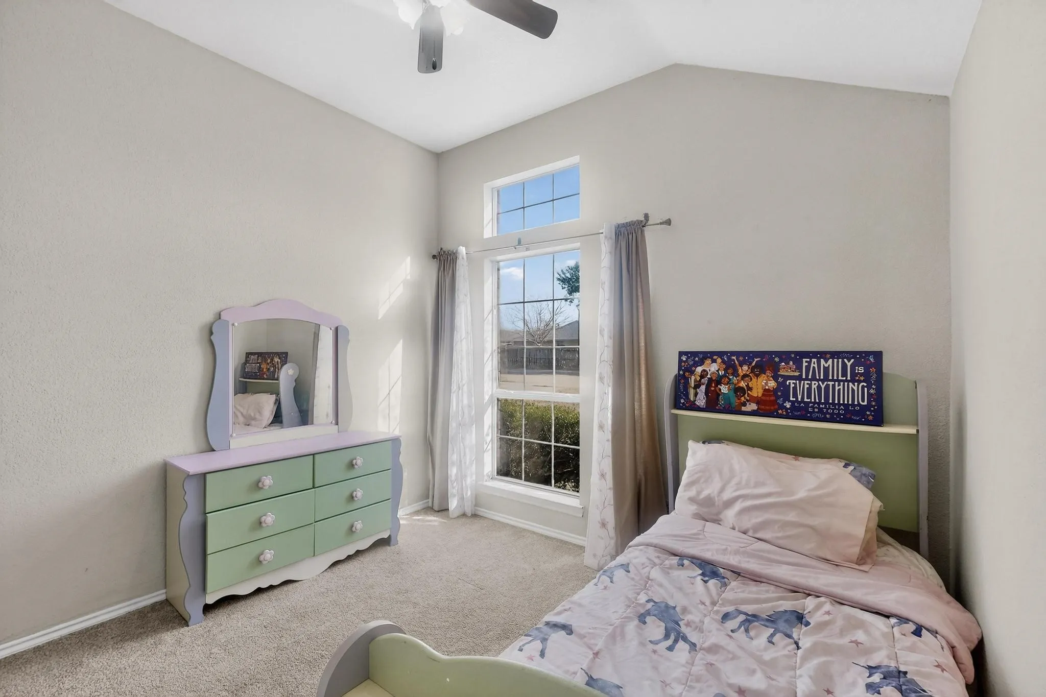 Vaulted ceiling with a ceiling fan, carpeted flooring, large window with transom, and neutral wall tones