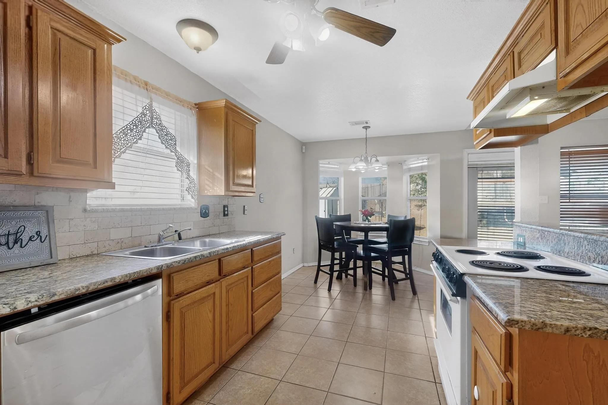 Kitchen featuring wood cabinetry, stainless steel sink, tile backsplash, and stone-finish countertops