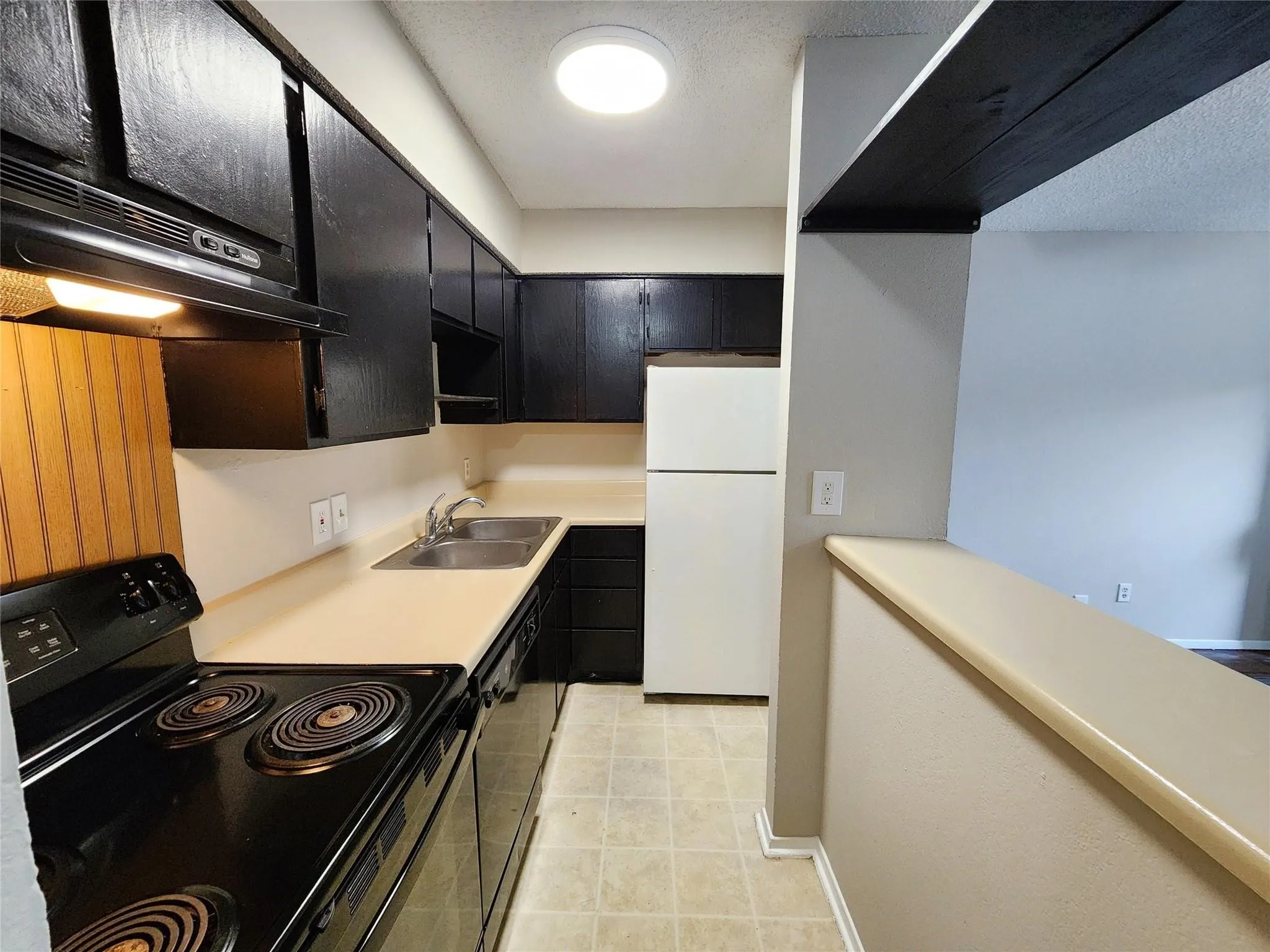Kitchen featuring black cabinetry, light countertops, and a white refrigerator