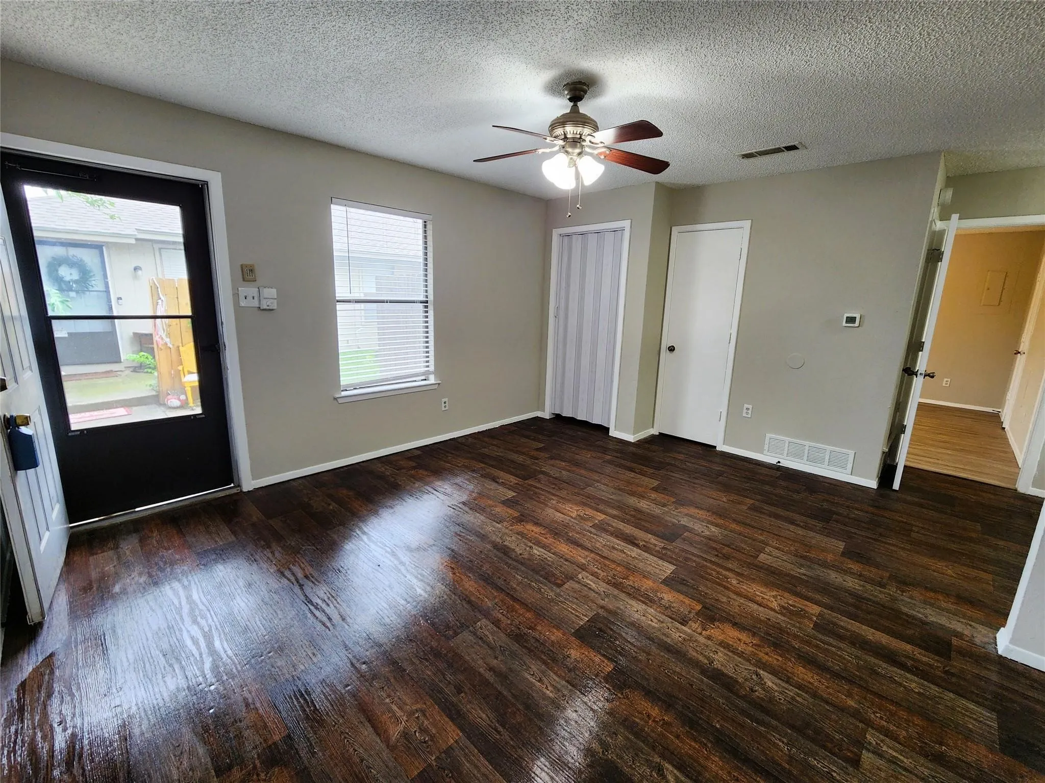 Wood-finish flooring throughout, ceiling fan with integrated lighting, window with blinds, and white trim accents