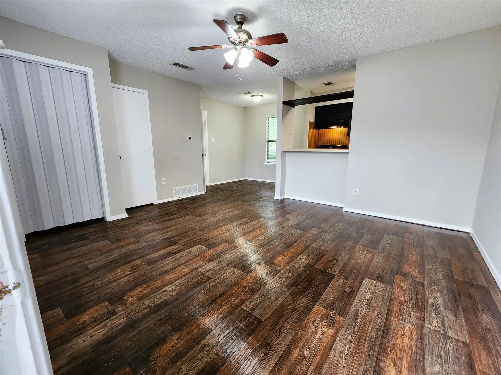 Wood-finish flooring throughout, light neutral wall paint, and a ceiling fan with light fixture