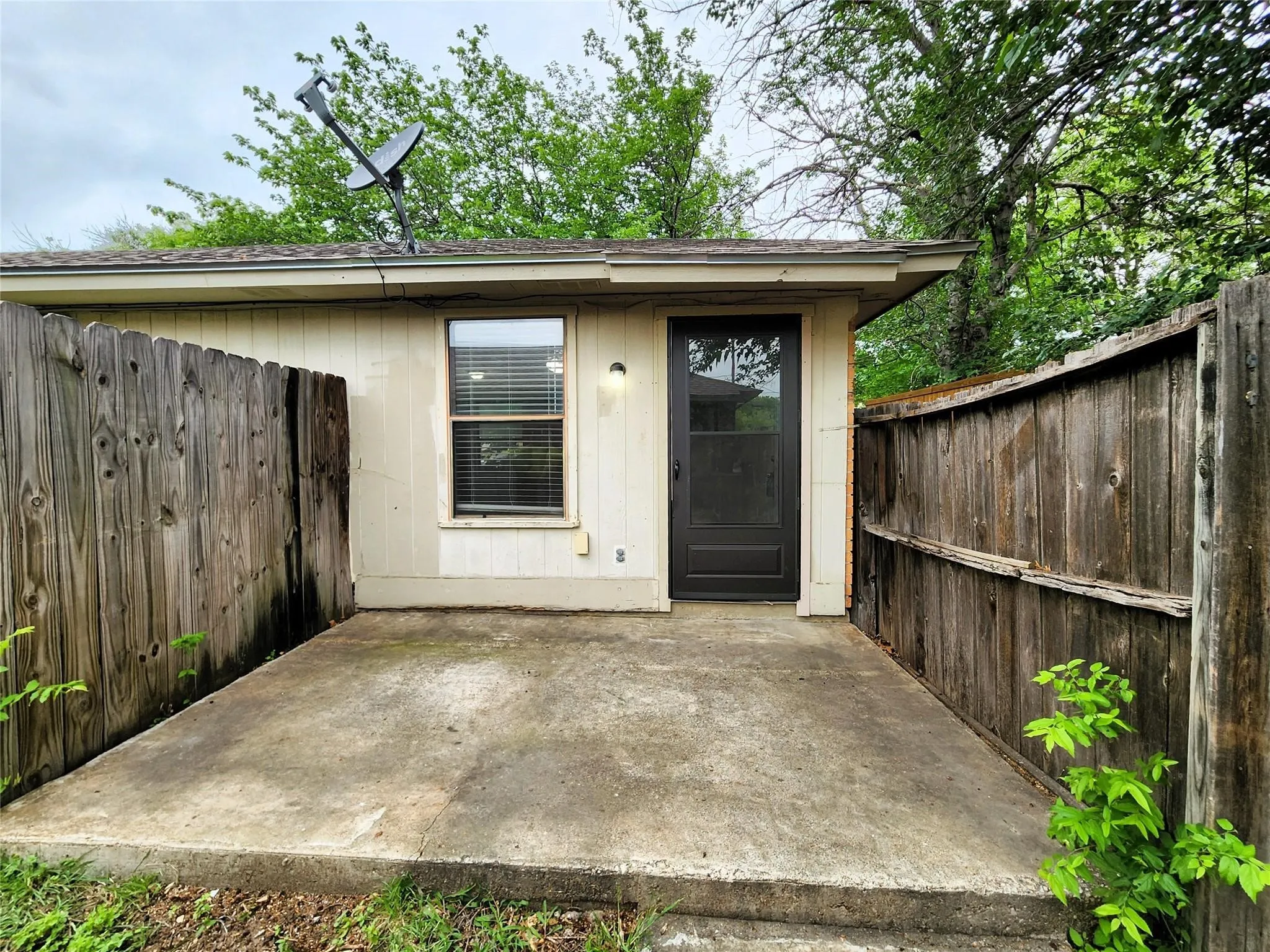 Private outdoor patio with concrete surface, surrounded by wood fencing