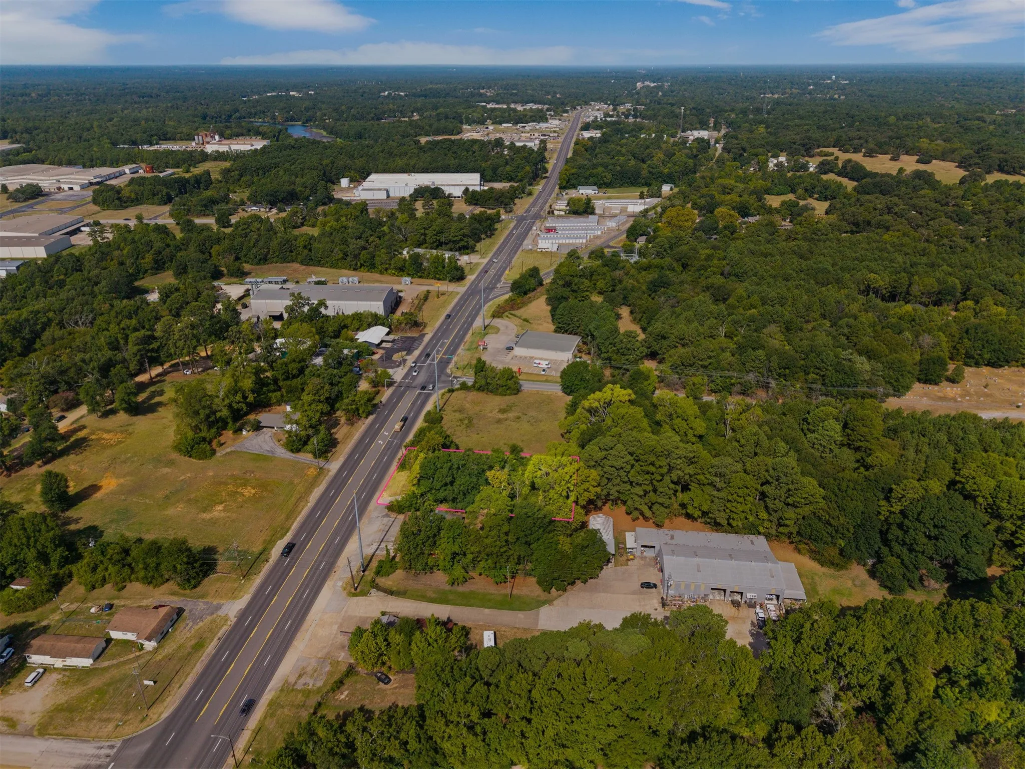 Expansive wooded acreage with undeveloped parcels and established commercial structures, featuring direct road frontage