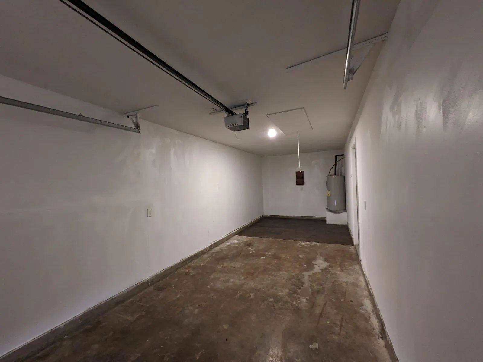 Garage featuring a garage door opener and electric water heater