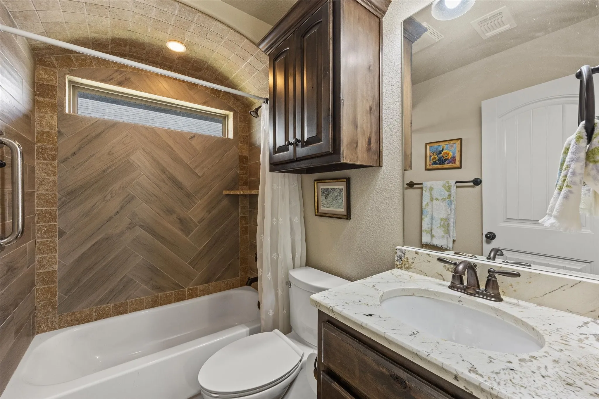 Bathtub with herringbone-patterned tile surround, accent border tile, and an arched ceiling detail