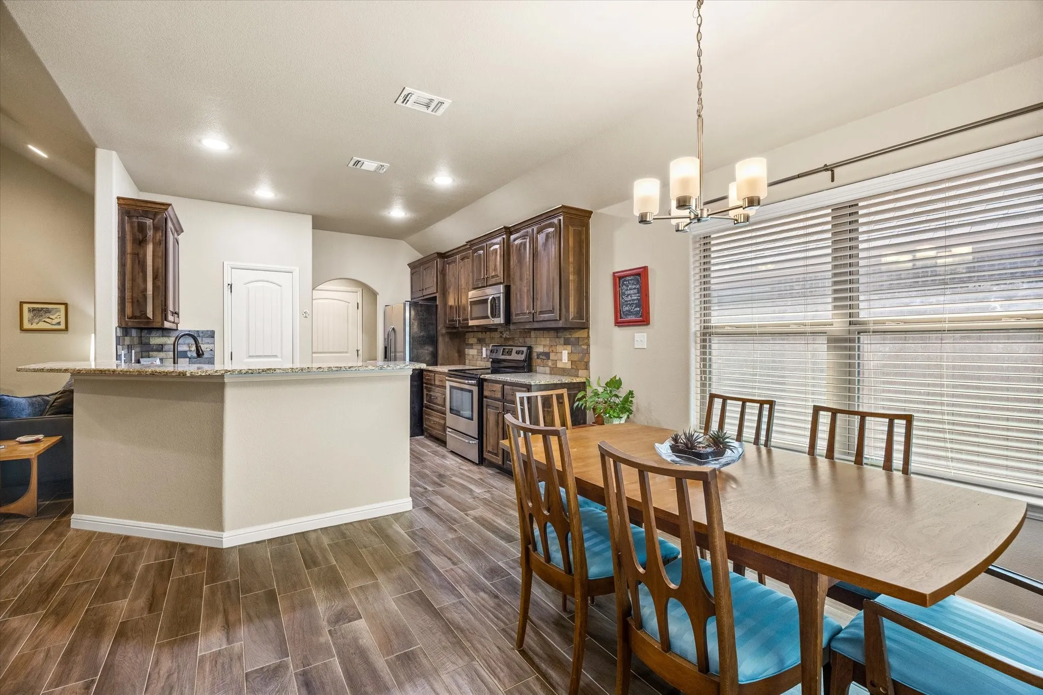 Wood-look tile flooring, recessed lighting, wood cabinetry, granite countertops, breakfast bar, stainless-steel appliances