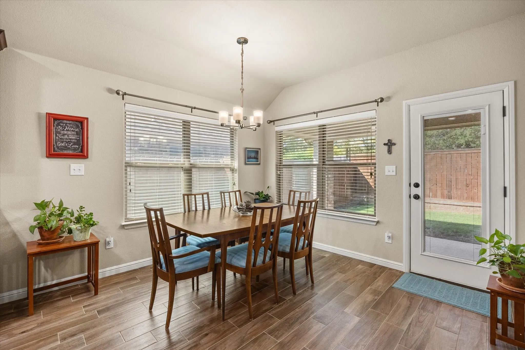 Wood-look tile flooring, multiple windows with blinds, and a glass-paneled exterior door