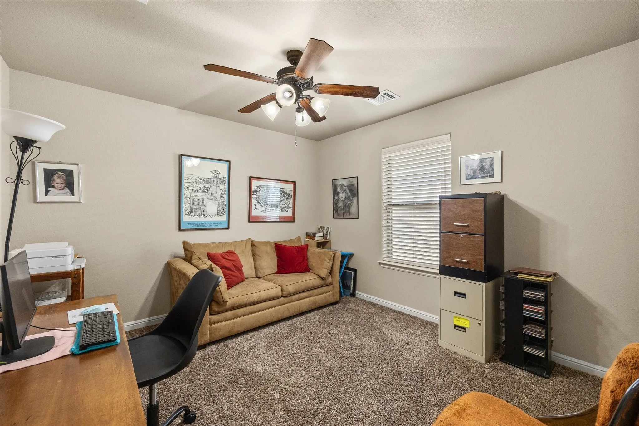 3rd bedroom with carpeted flooring with a ceiling fan light fixture and window with blinds - currently used as office or study