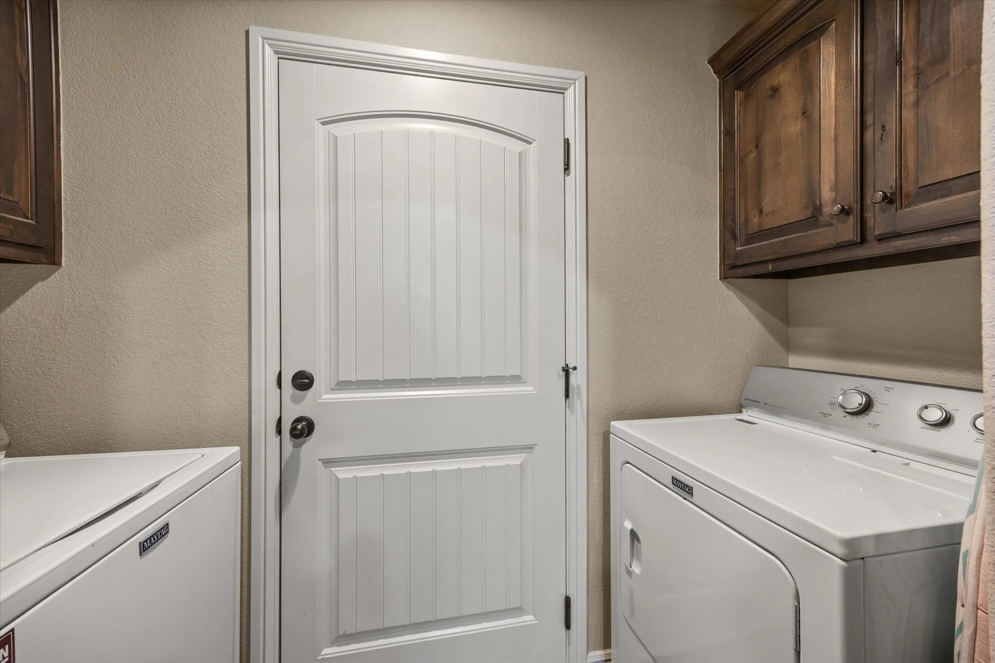 Laundry area featuring wood-finish cabinetry, and neutral wall tones