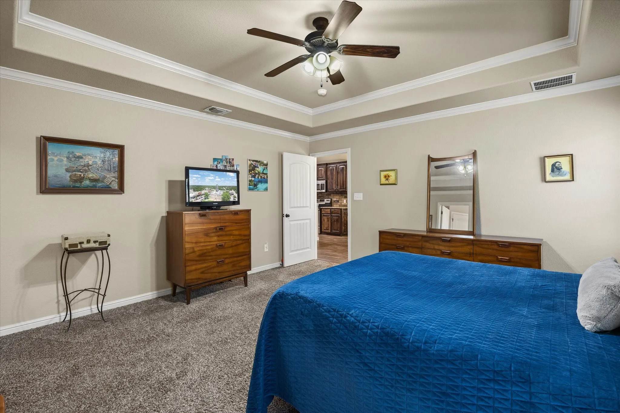 Tray ceiling with crown molding, ceiling fan, and carpeted flooring