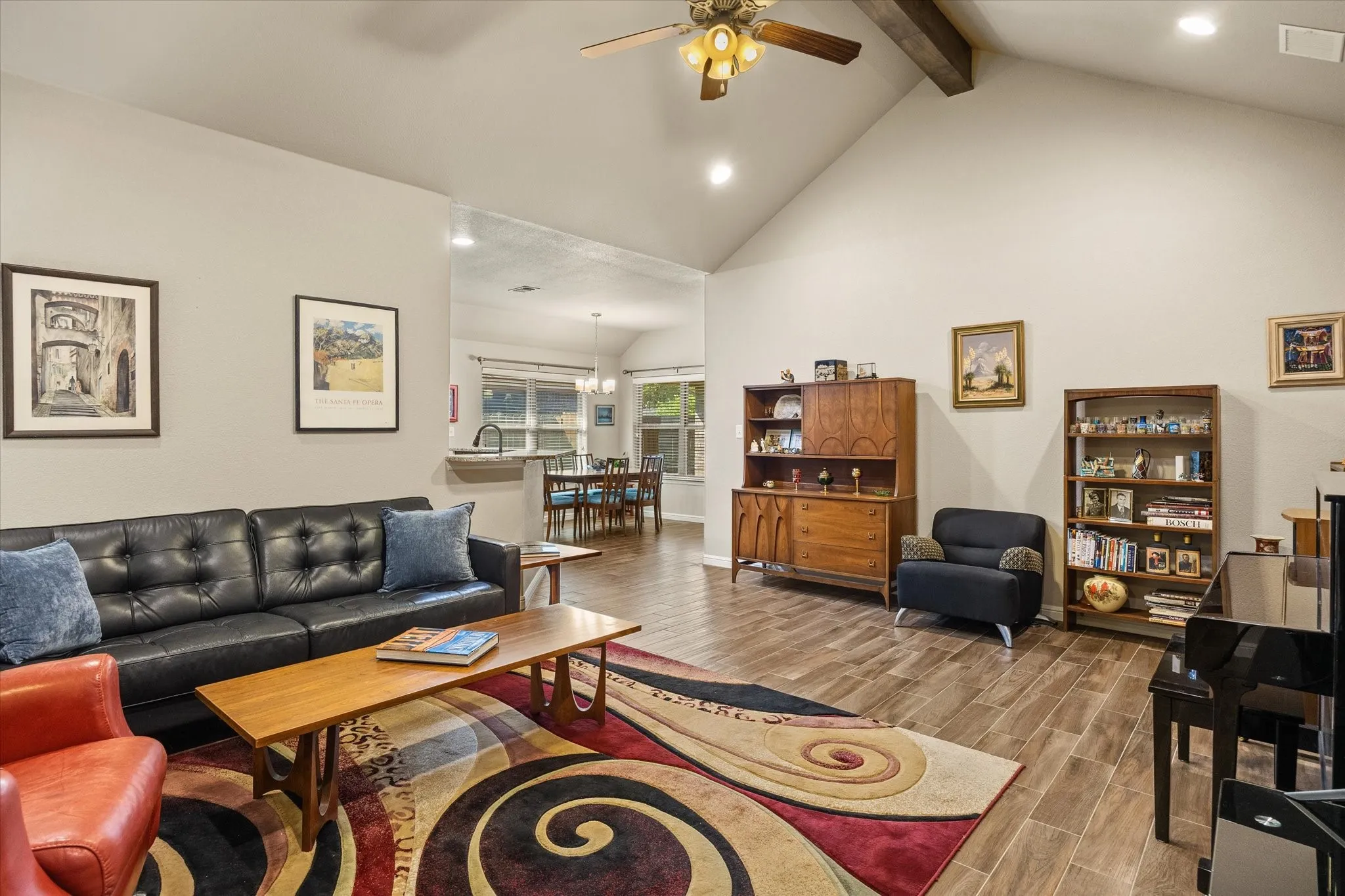 Vaulted ceiling with exposed wood beam, wood-look tile flooring, recessed lighting, and ceiling fan