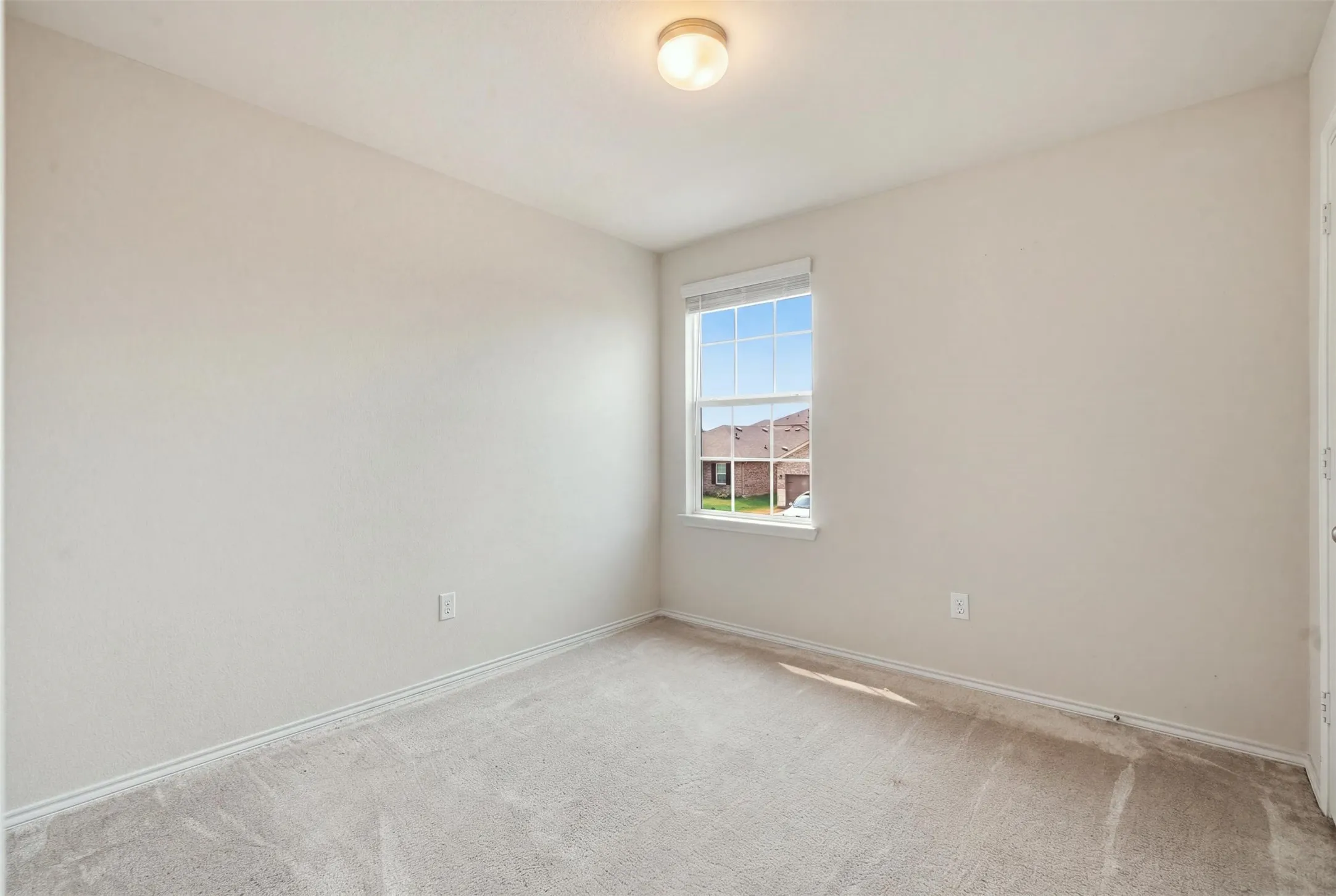 Spacious bedroom with plush carpeting, recessed lighting, and a soft neutral color palette
