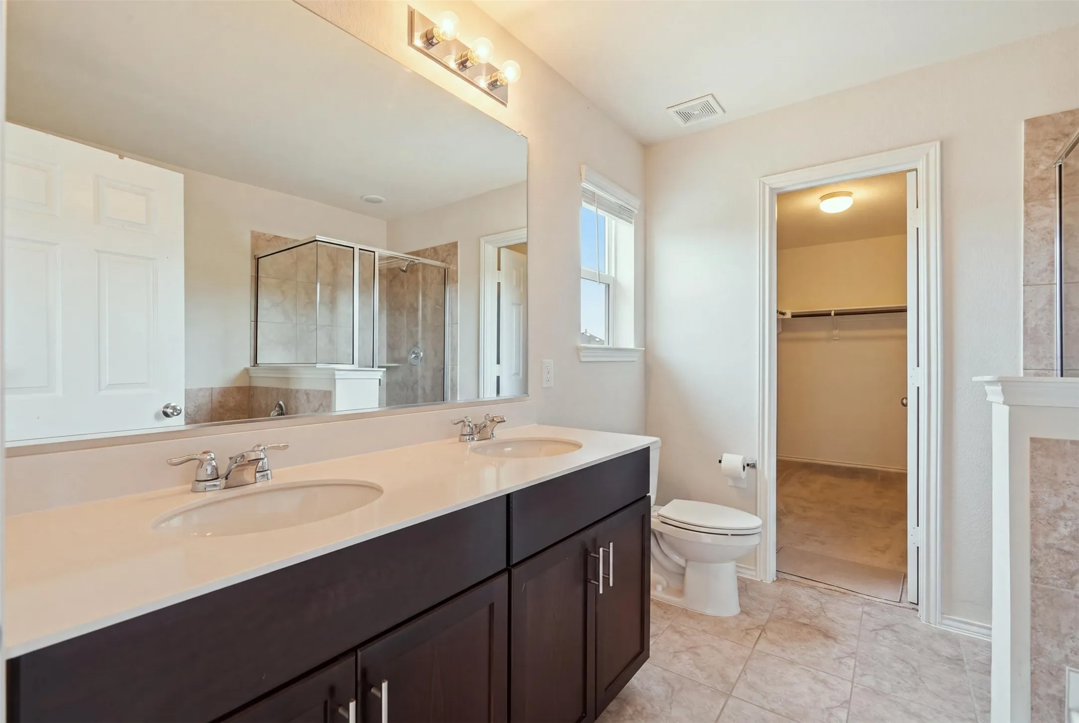 Elegant dual vanity with rich dark cabinetry, a light-toned countertop, and sleek chrome fixtures for a polished finish
