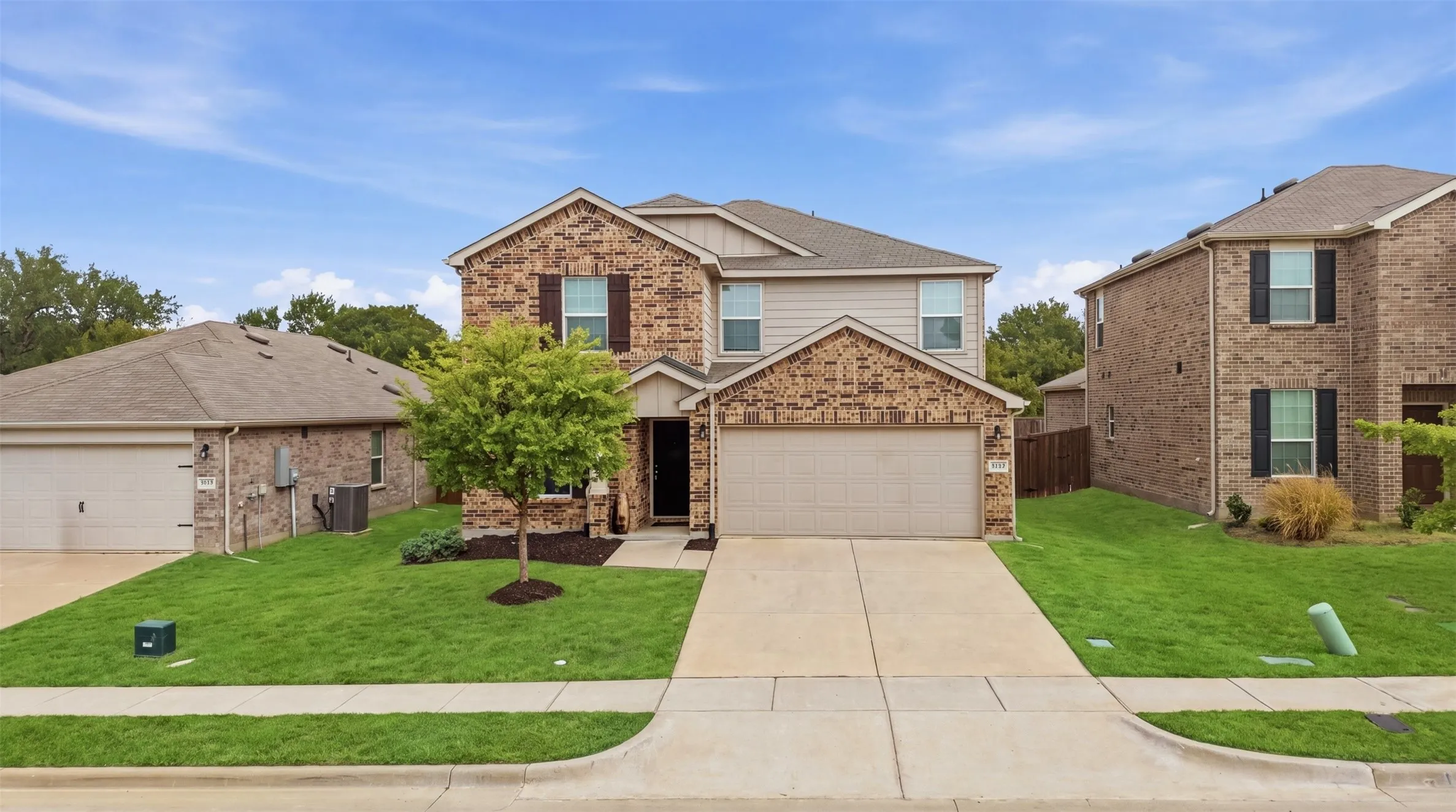 Inviting brick-and-siding exterior with a two-car garage, mature landscaping, and a welcoming entryway
