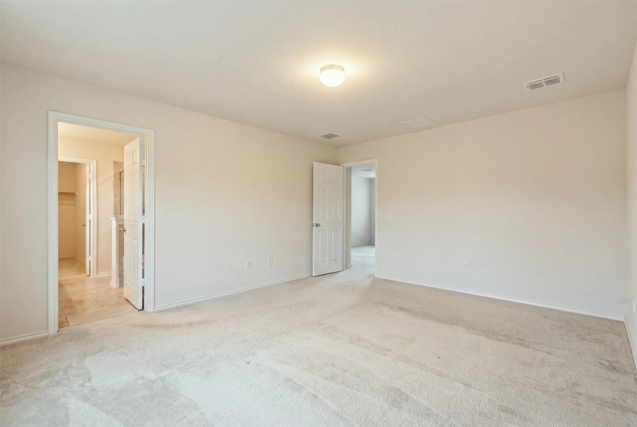 Primary bedroom with light-toned carpeting, large windows, recessed lighting, and neutral walls

