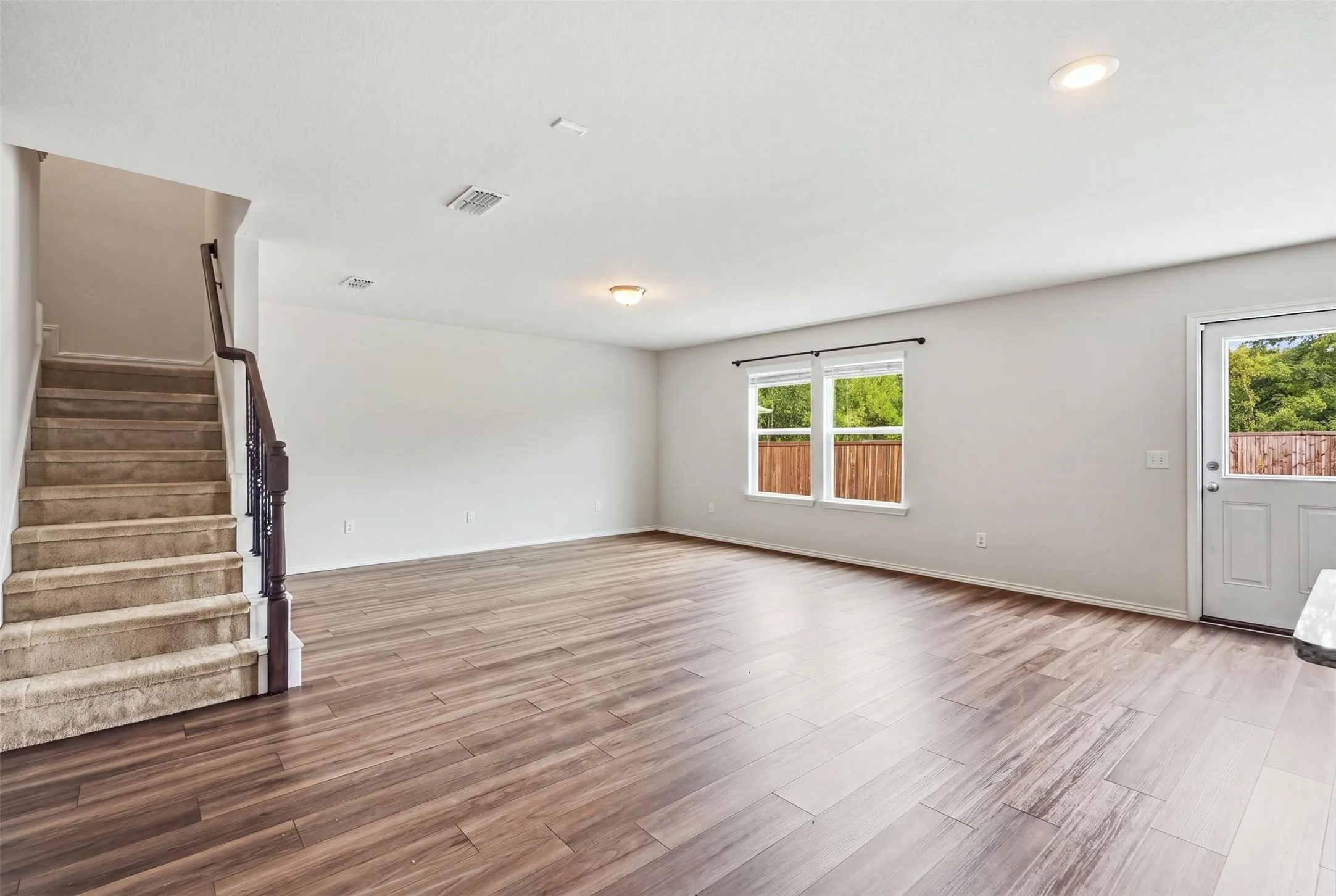 Open-concept living area with rich wood-look flooring, recessed lighting, and a classic white paneled door for a warm, polished look