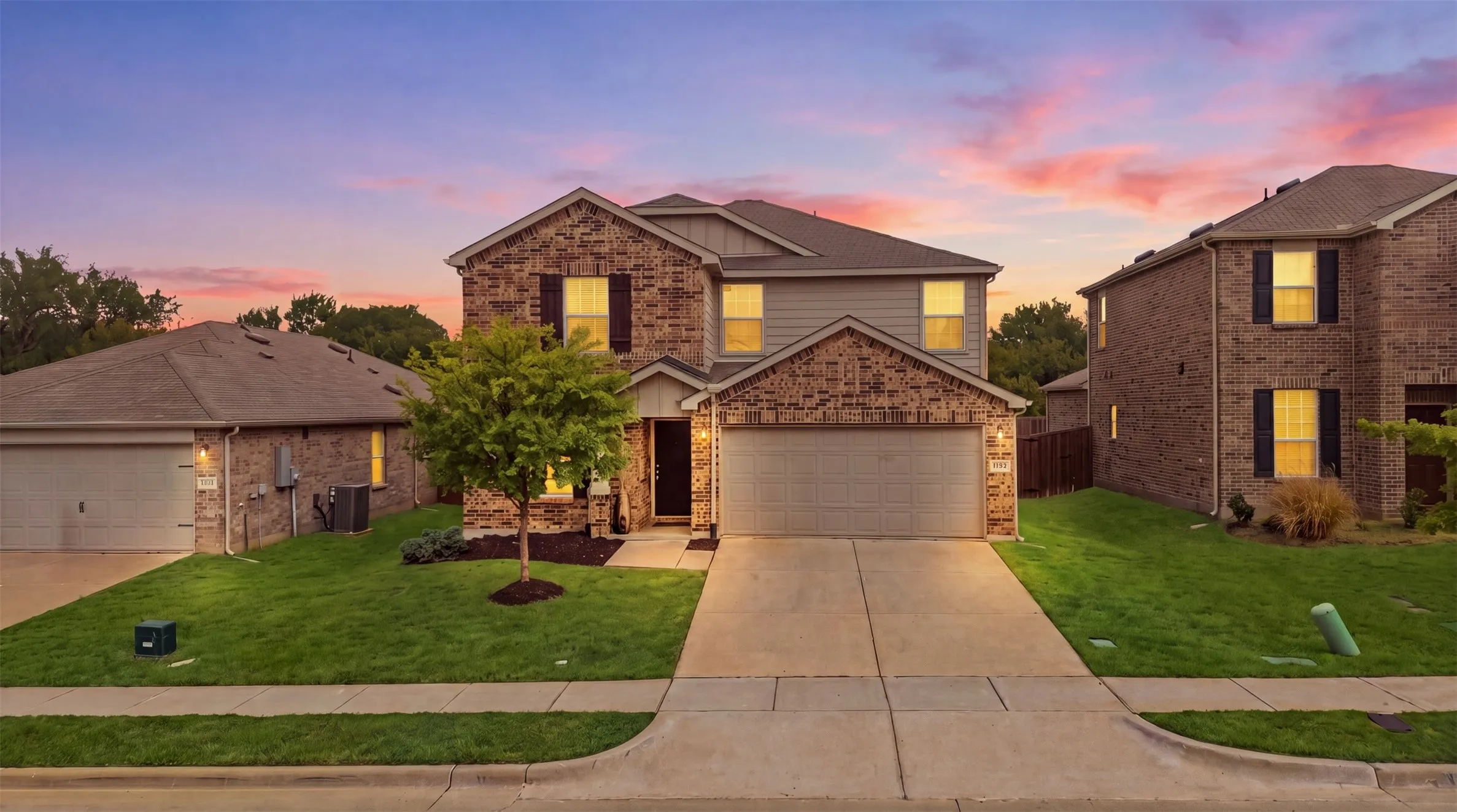 Charming brick-and-siding exterior with dark shutters, an attached garage, and a welcoming concrete driveway