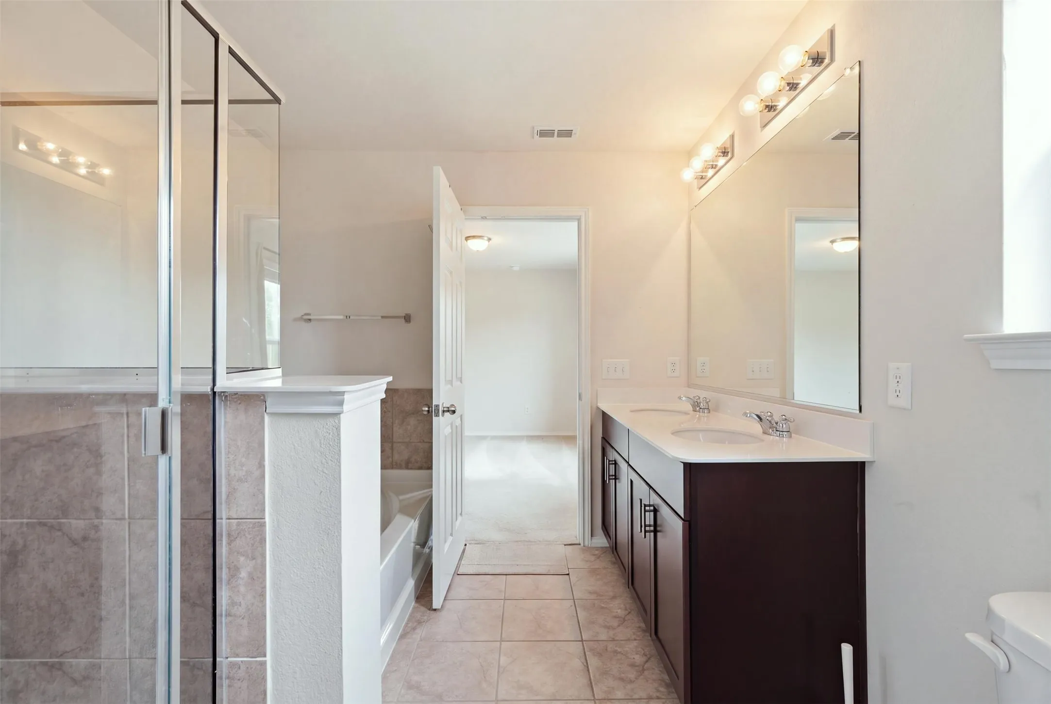 Elegant dual vanity with dark wood cabinetry, integrated sinks, and polished chrome faucets