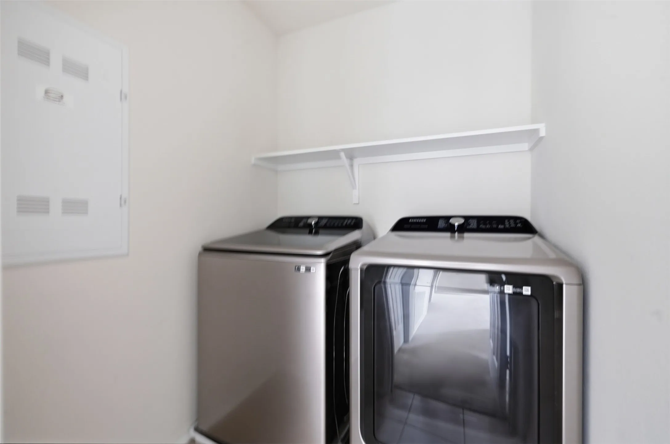 Bright laundry room with clean white walls and a sleek wall-mounted shelf for added storage
