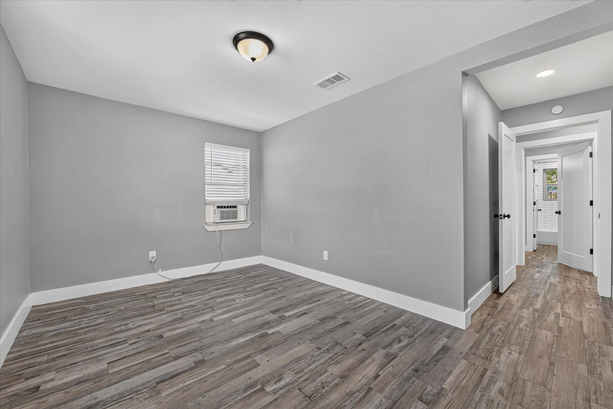 Light gray painted walls, wood-finish flooring, white trim, and a ceiling-mounted light fixture