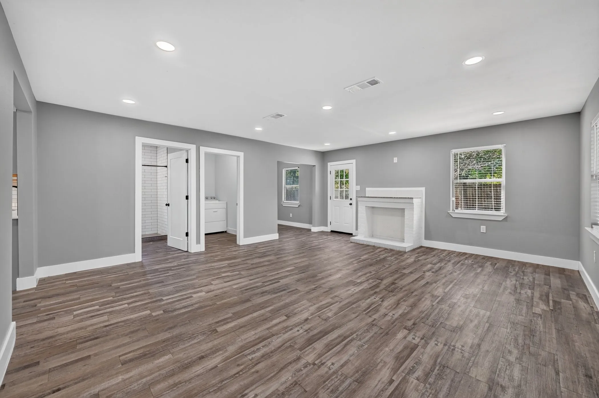 Spacious living area featuring wood-finish flooring, recessed lighting, and a white fireplace
