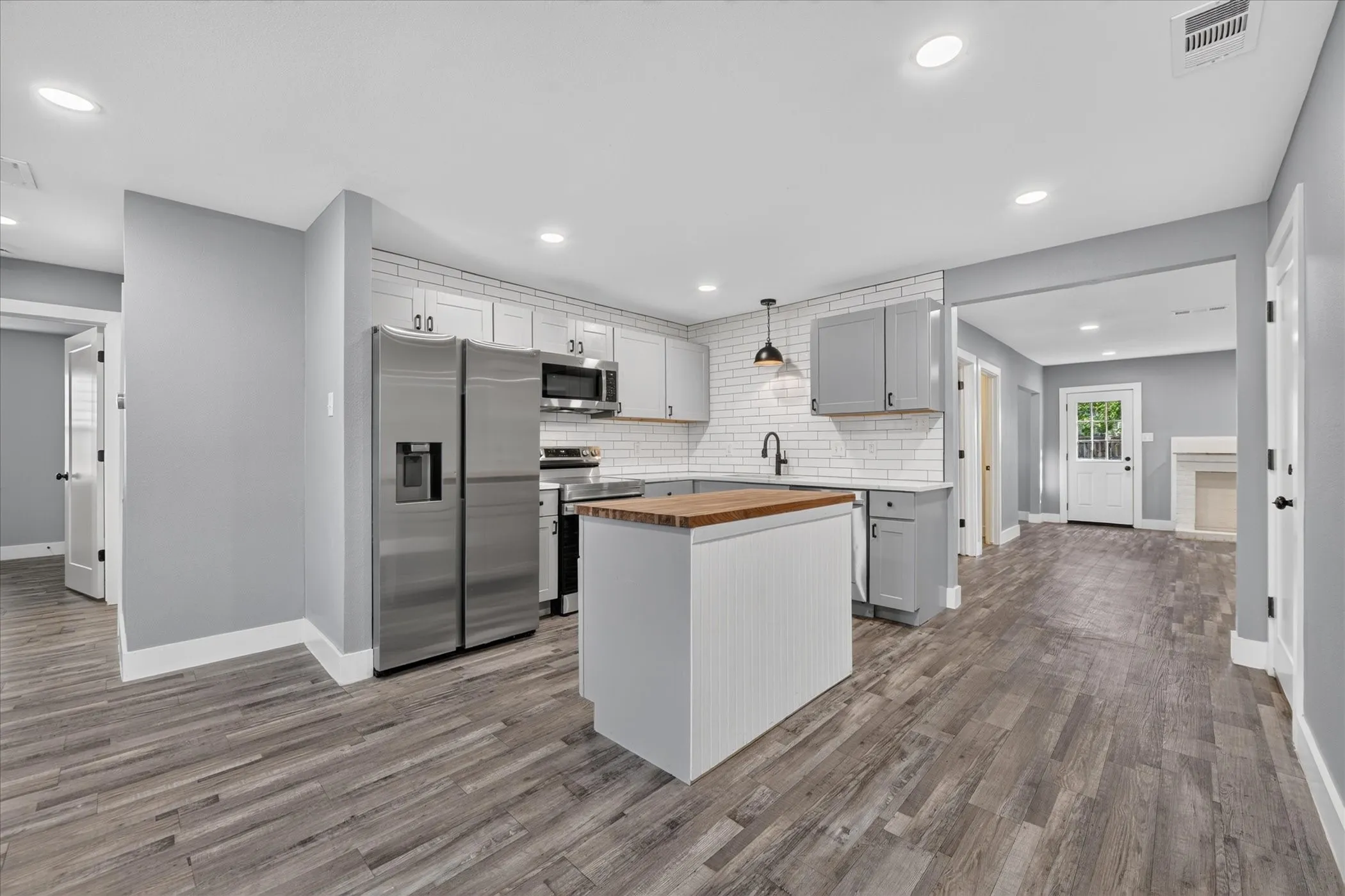 Updated kitchen with stainless steel appliances, a wood-finish island countertop, white subway tile backsplash, and recessed lighting