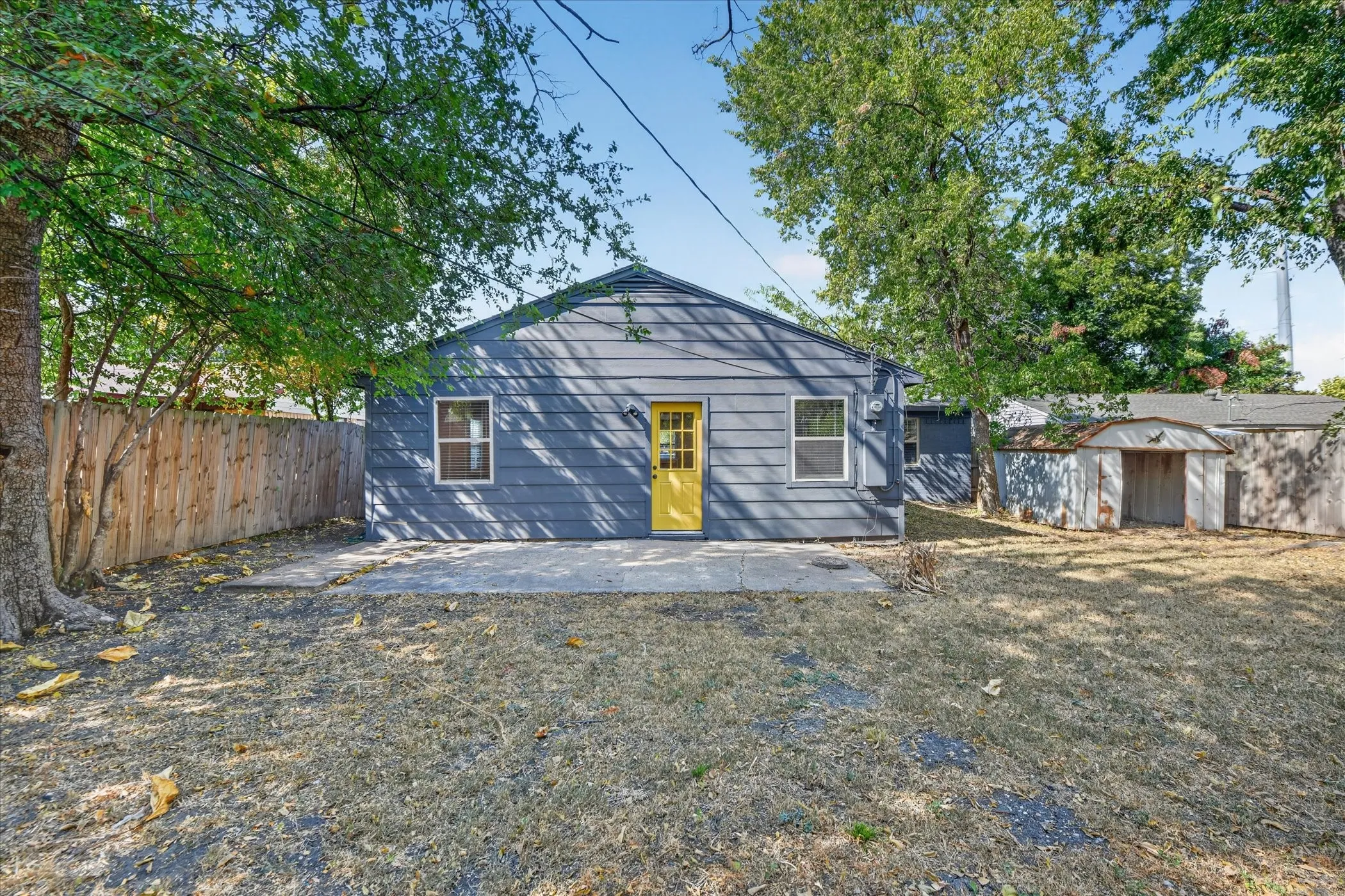 Rear exterior featuring horizontal siding, a yellow paneled door, and multiple windows
