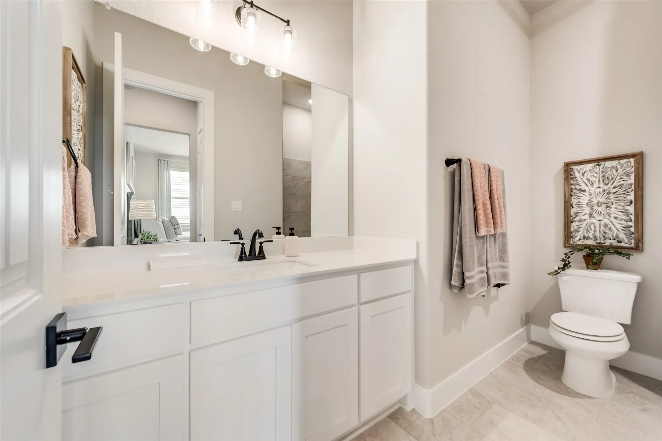 White vanity with a solid surface countertop and matte black faucet