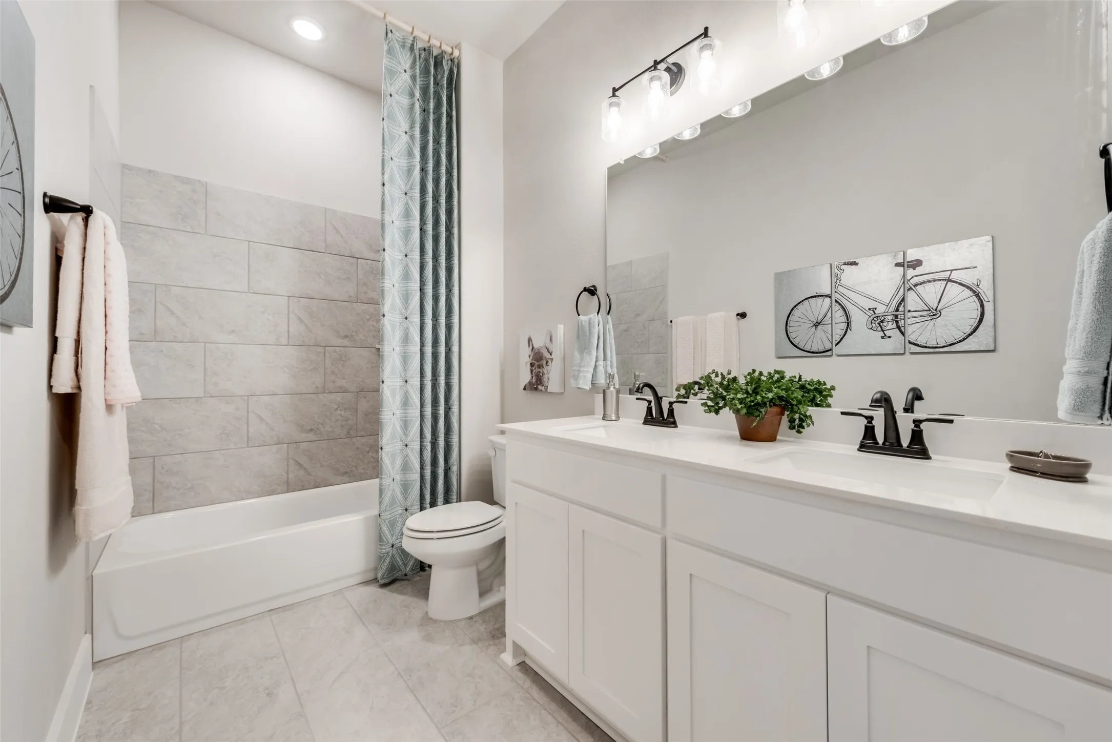 Dual vanity with white cabinetry, matte black hardware, and an expansive mirror