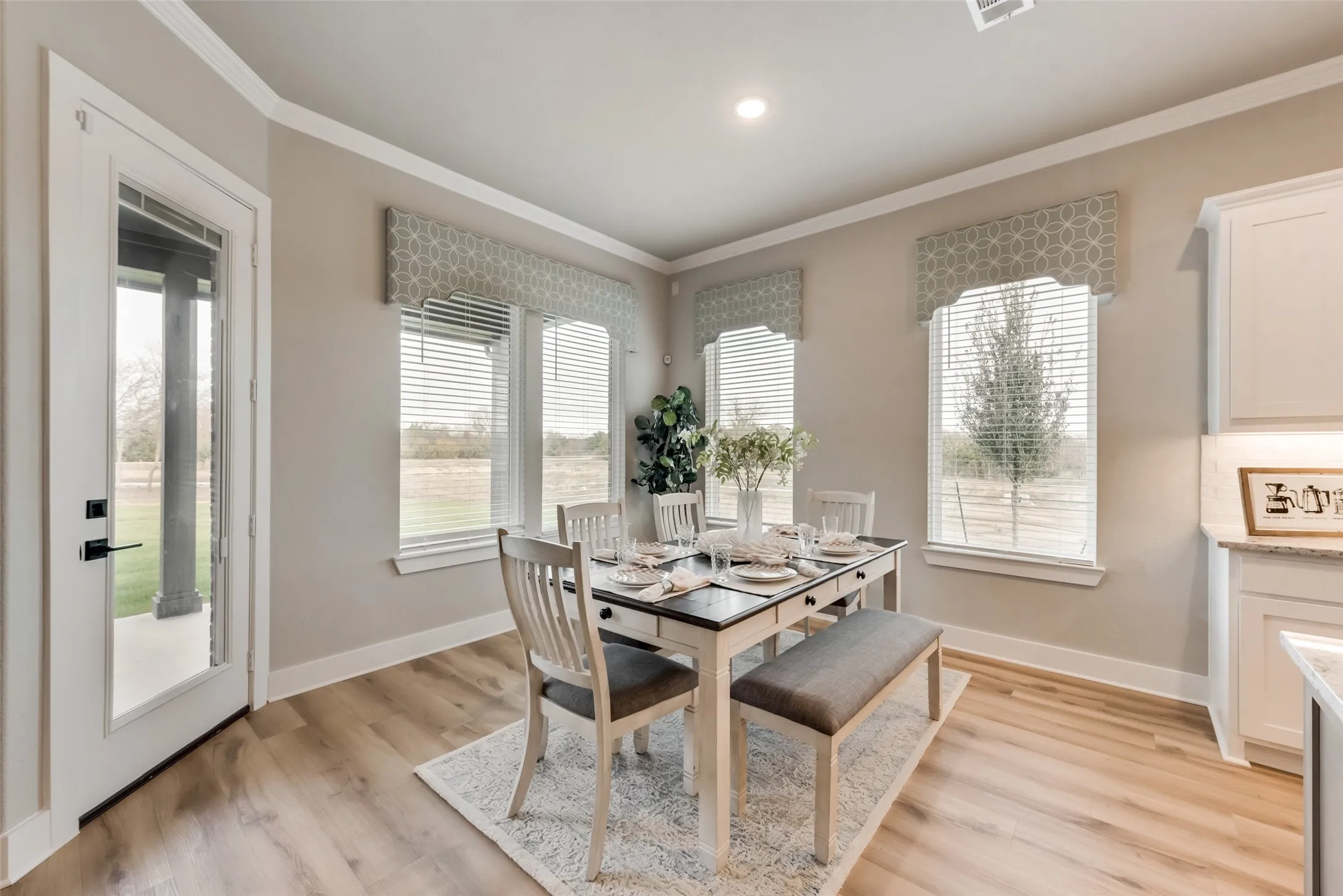 Wood-finish flooring, crown molding, double windows, recessed lighting, and a full-light exterior door