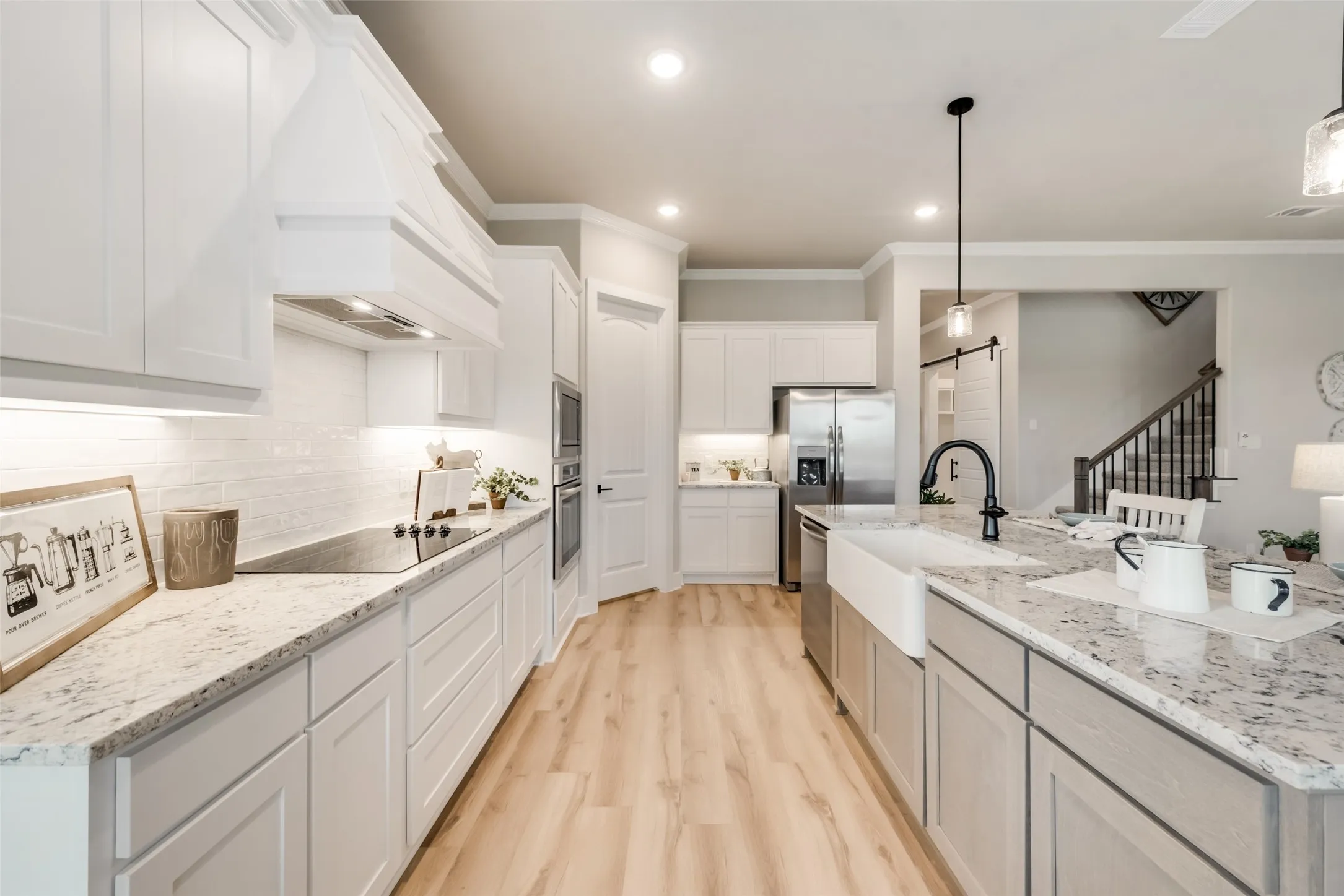 Gourmet kitchen featuring a large center island, white cabinetry, integrated appliances, wood-finish flooring, and a subway tile backsplash