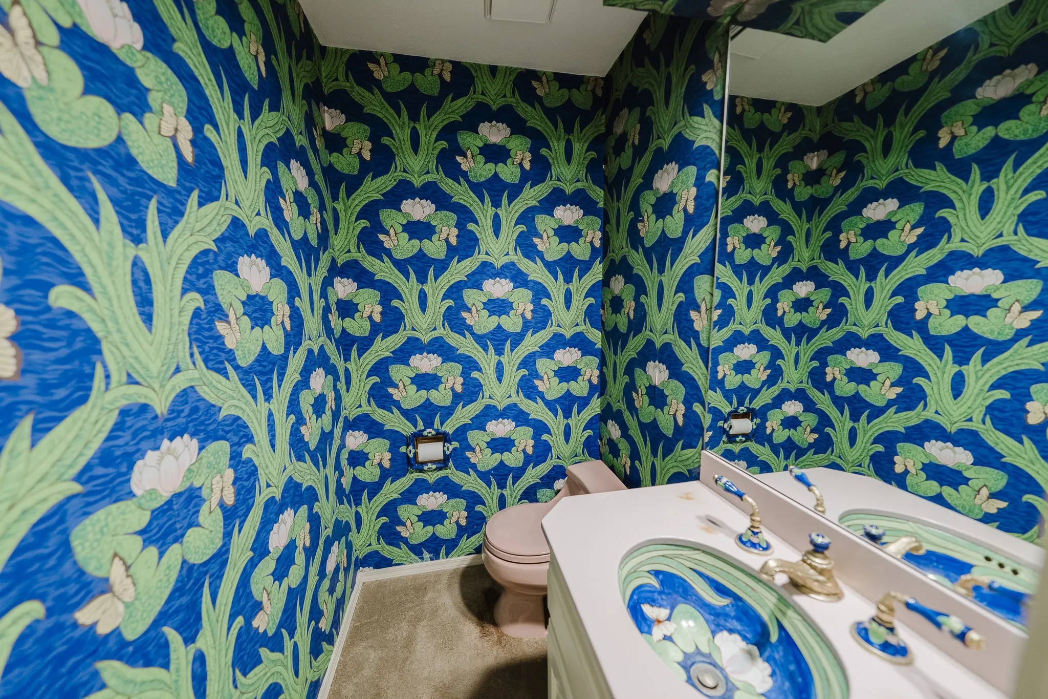 Patterned wallpaper, recessed lighting, vanity with integrated basin, decorative sink faucets, wall-mounted mirror