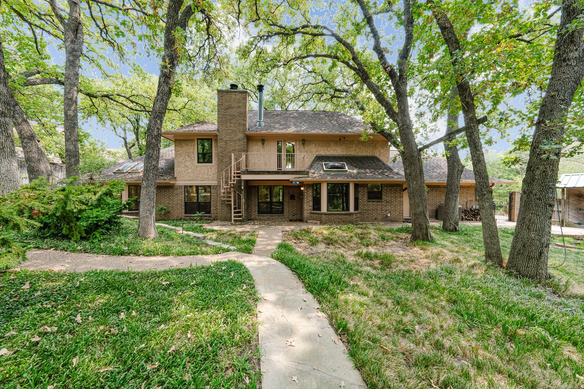 Traditional brick and stucco exterior with multiple windows, a prominent brick chimney, and a spiral staircase