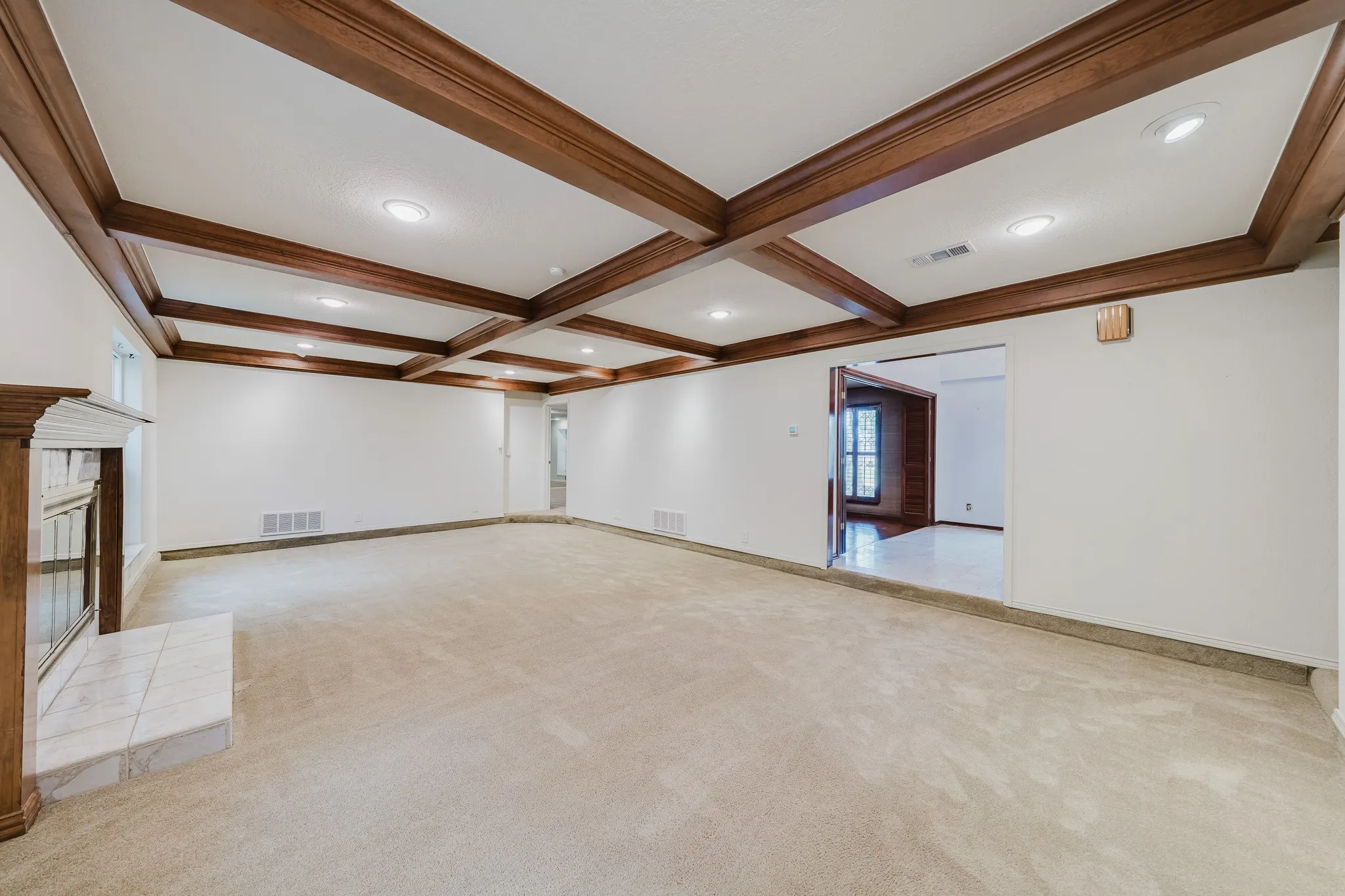 Coffered ceiling with recessed lighting, wood-finish mantel, tiled fireplace surround, and wall-to-wall carpeting