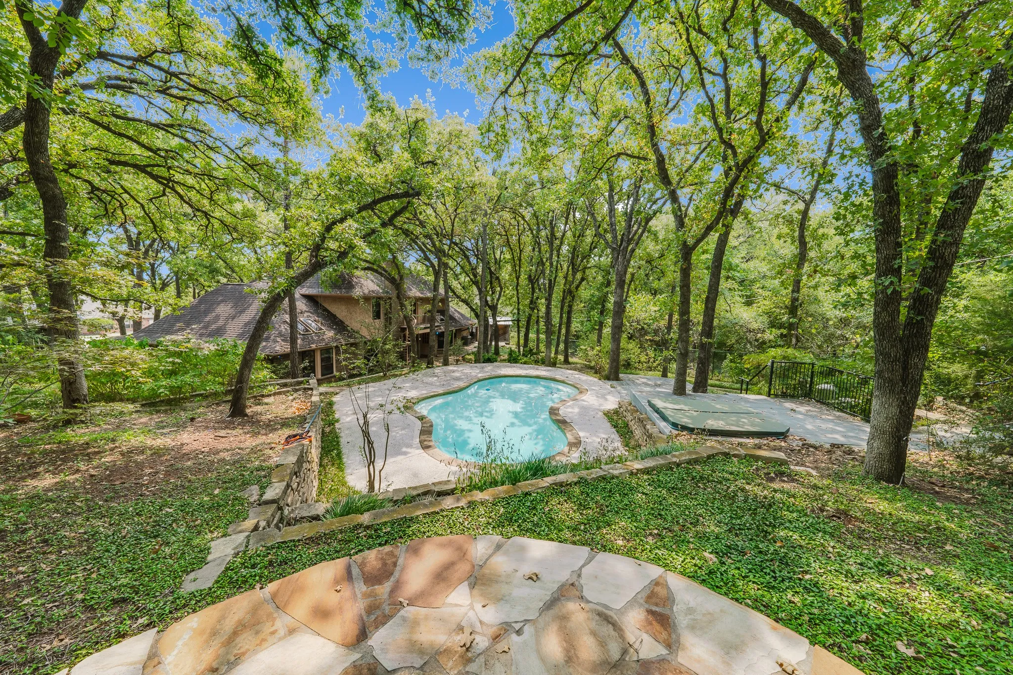 Backyard oasis featuring a freeform swimming pool, integrated spa, and mature trees