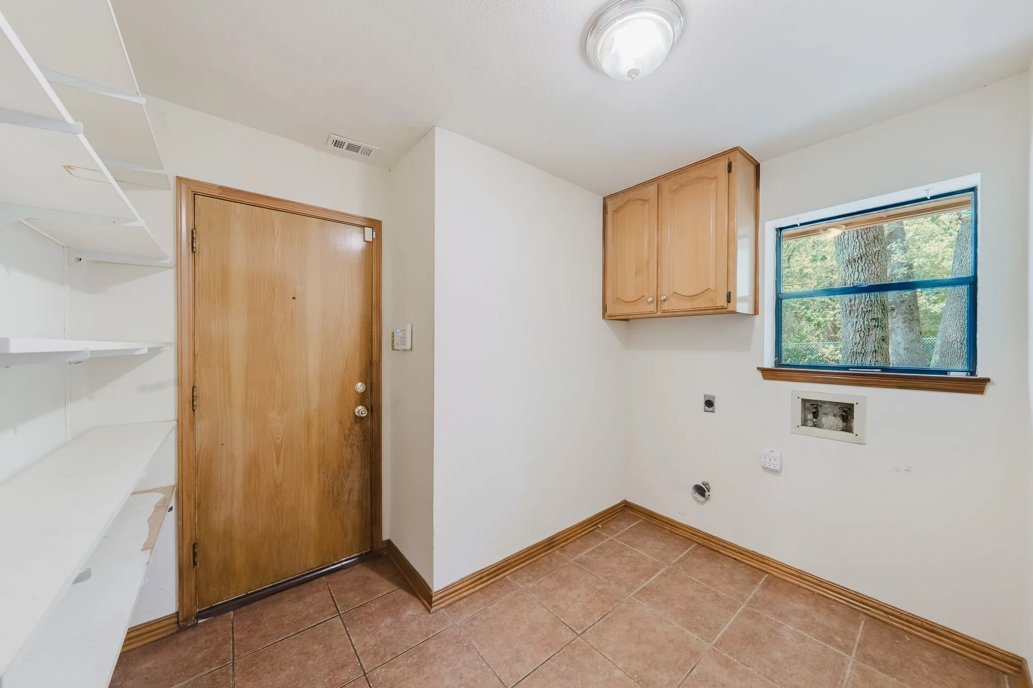 Room featuring light wood cabinetry, tiled flooring, built-in shelving, and a window