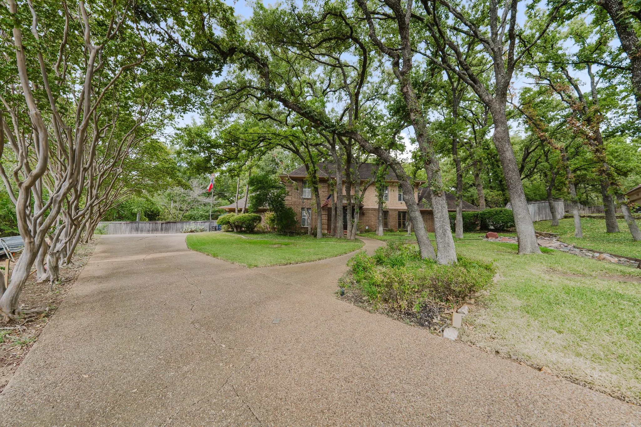 Expansive property with a long driveway, mature trees, manicured lawn, and brick exterior