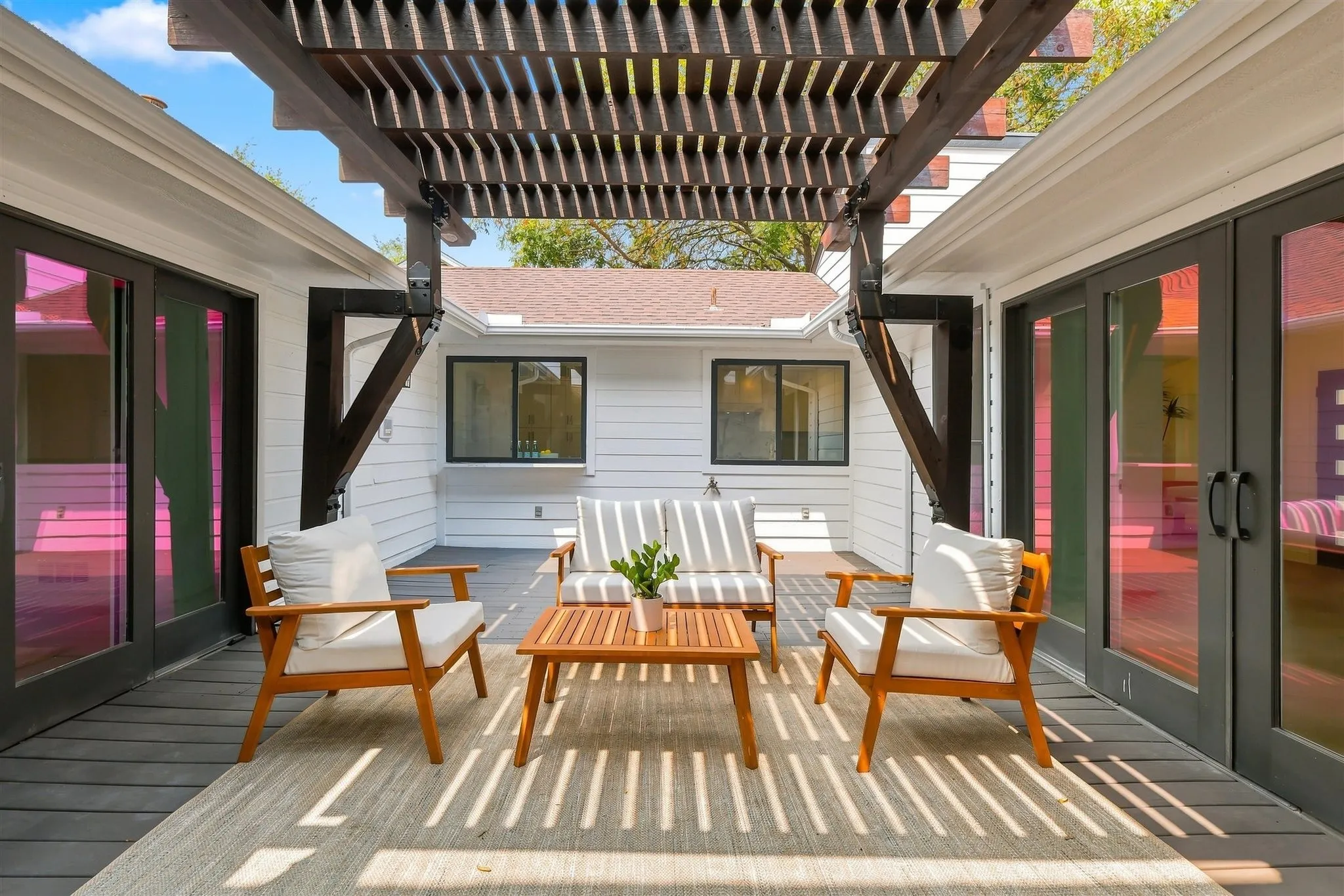 Expansive outdoor deck featuring a decorative pergola, durable composite decking, and dual sets of glass panel doors