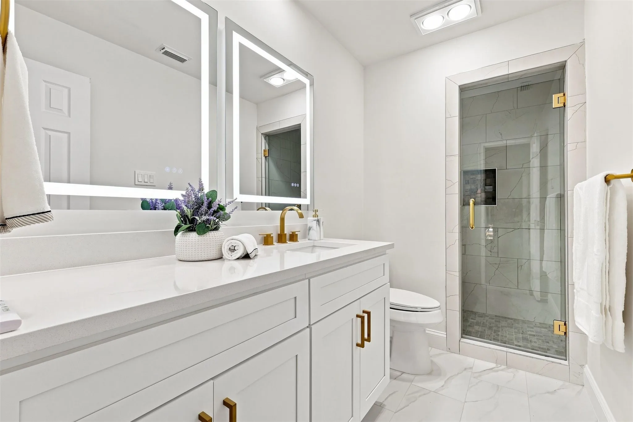 White shaker vanity with gold-finish hardware, quartz countertop, and integrated sink