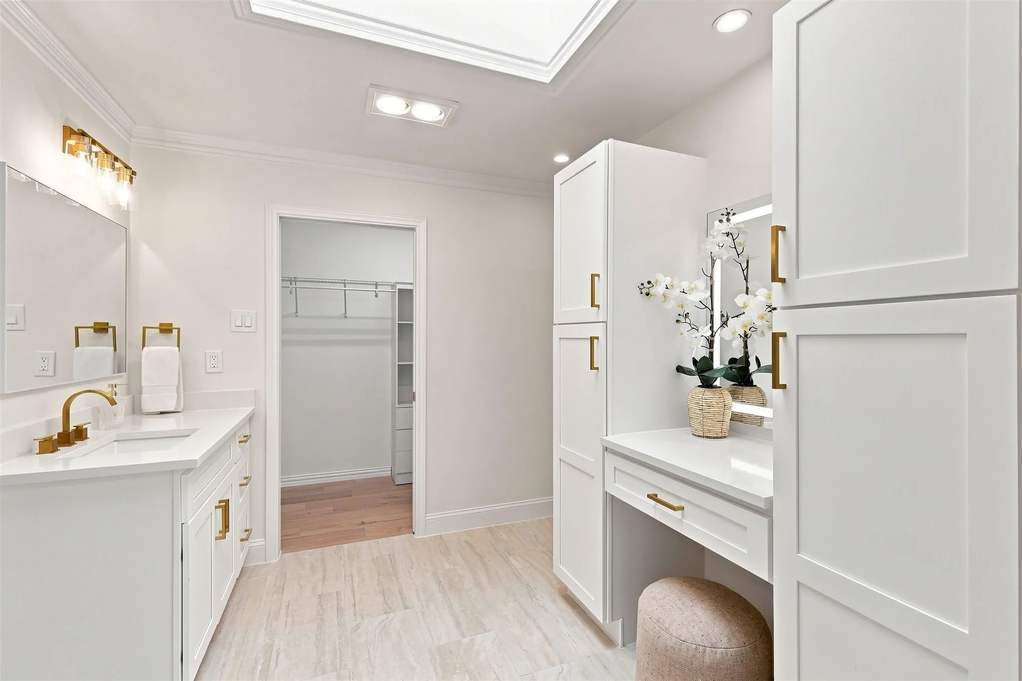 White cabinetry with gold-finish hardware, single vanity with white countertop, recessed lighting, and a skylight